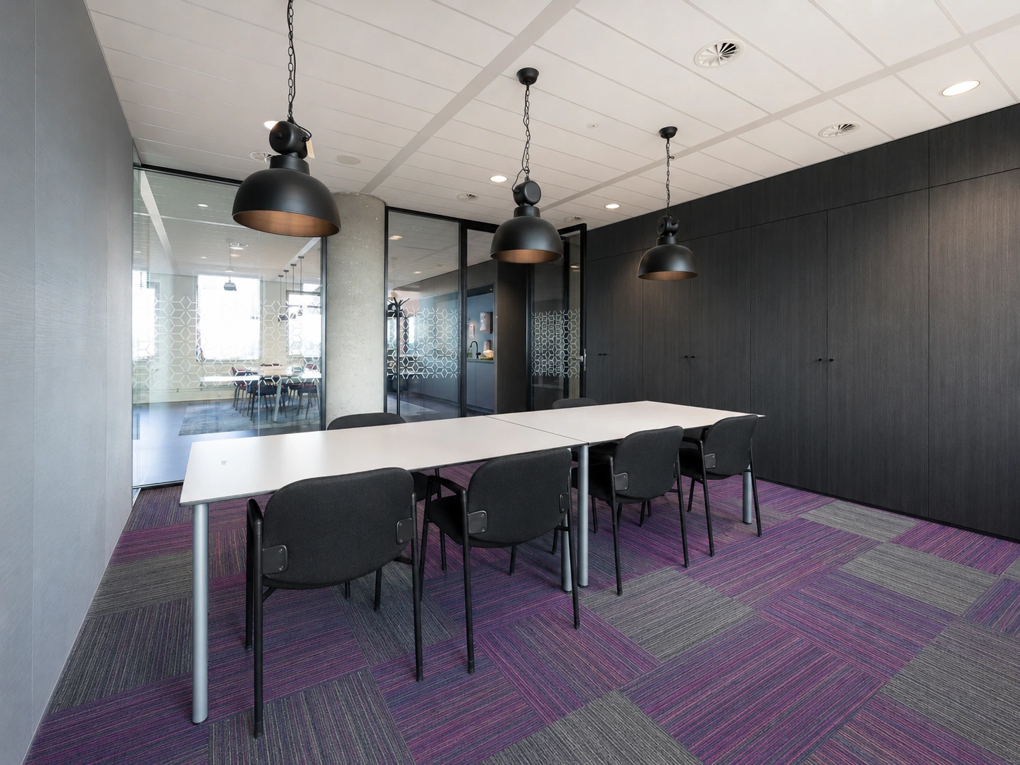 Purple and green carpet tiles beneath a long meeting table