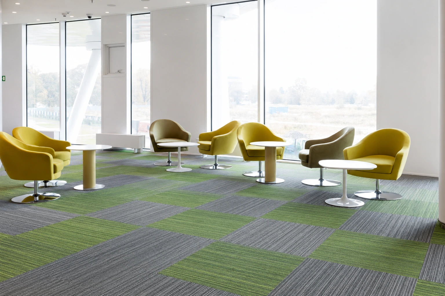 Green and grey designer carpet tiles in a breakout area with yellow chairs