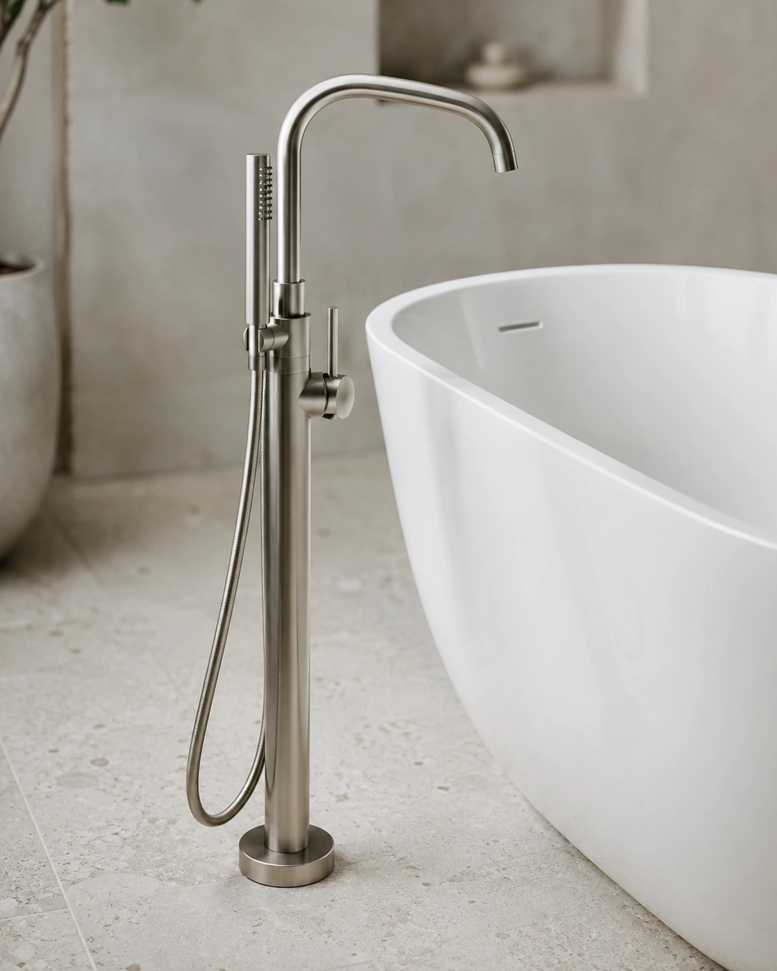 Brushed nickel freestanding tub faucet beside a white oval bath