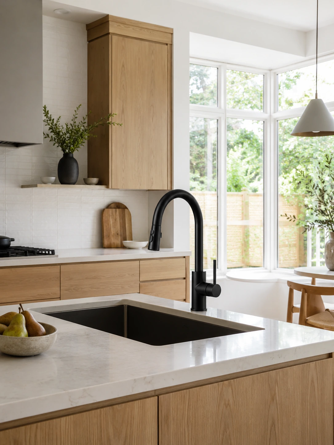Matte black pull-down faucet on a pale counter in an oak kitchen