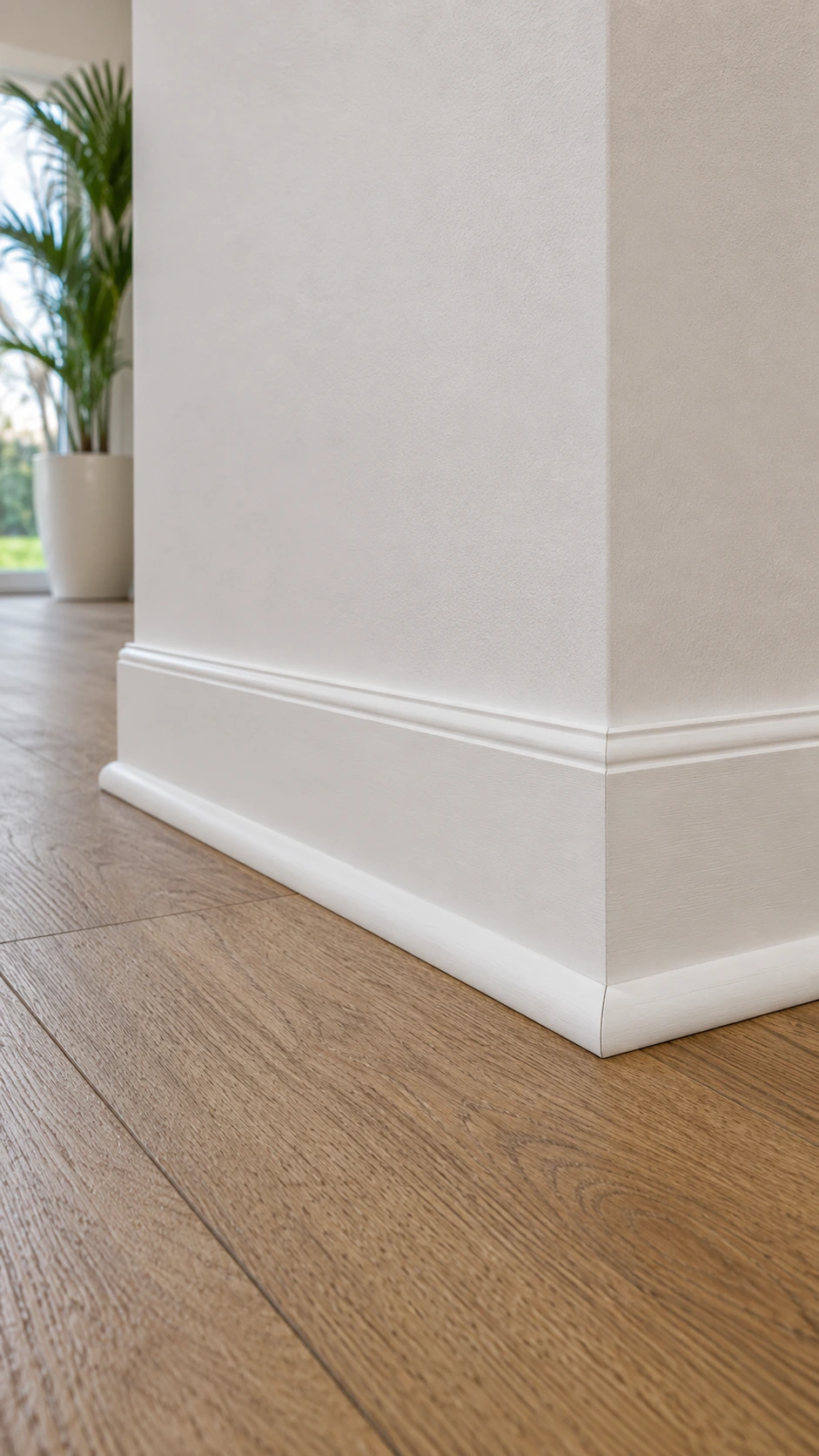Close view of white quarter round moulding on wood flooring