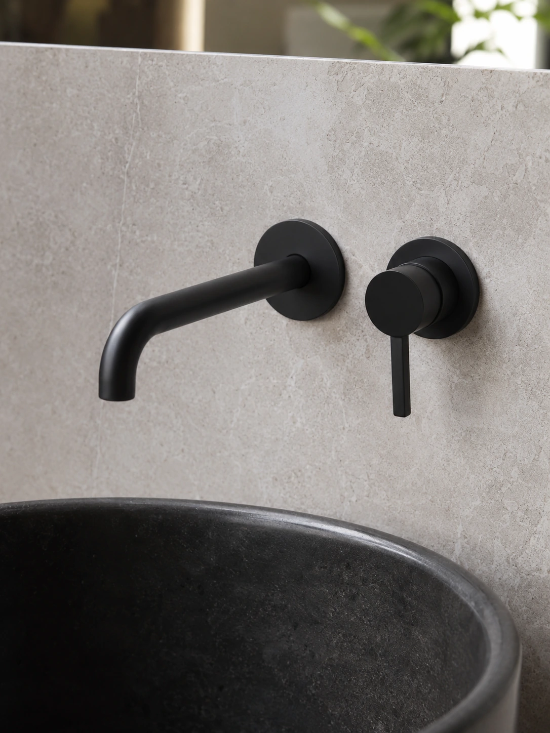 Matte black wall mounted faucet above a dark stone basin