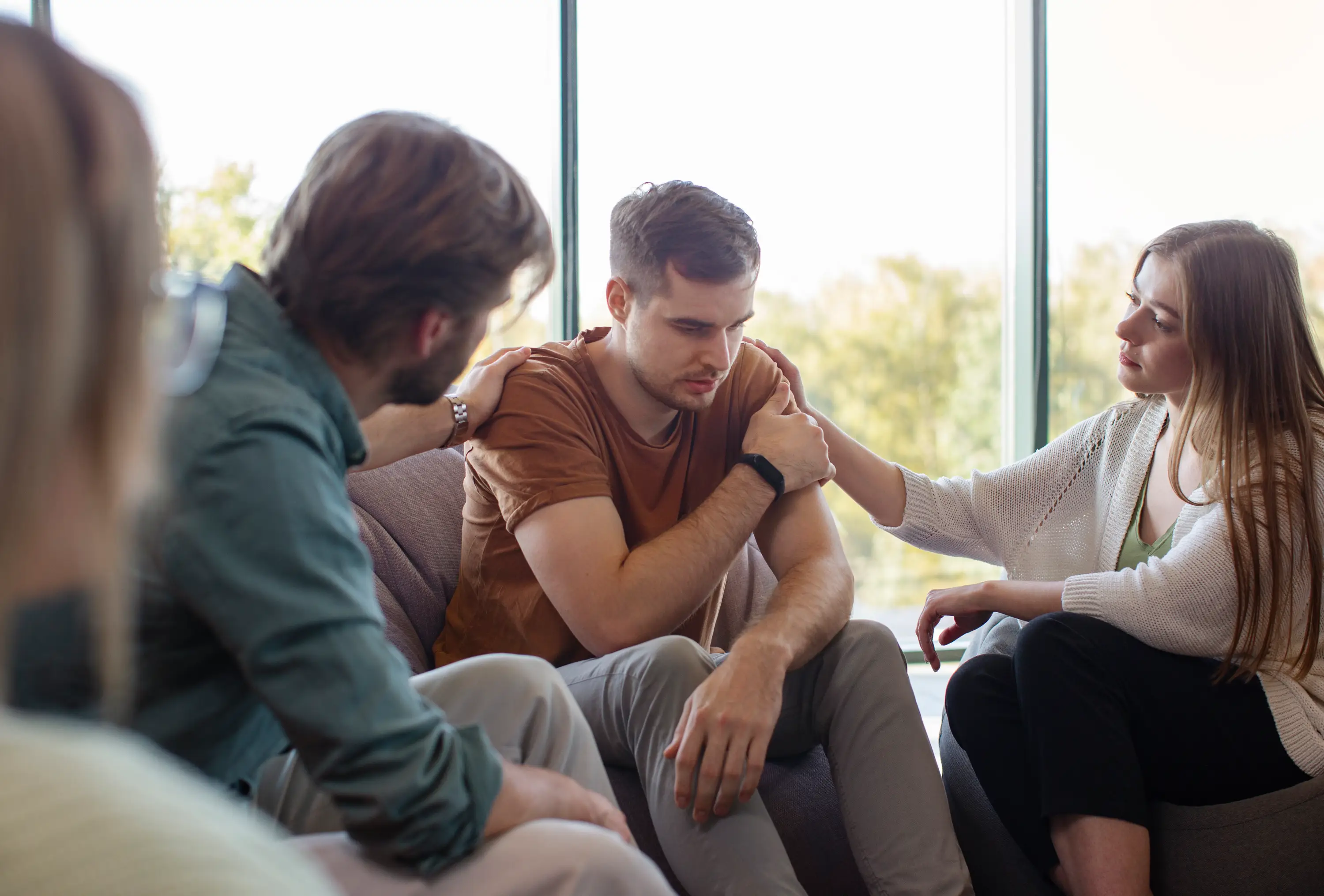 Teenage boy in beige hoodie sitting on couch smiling during conversation with therapist.