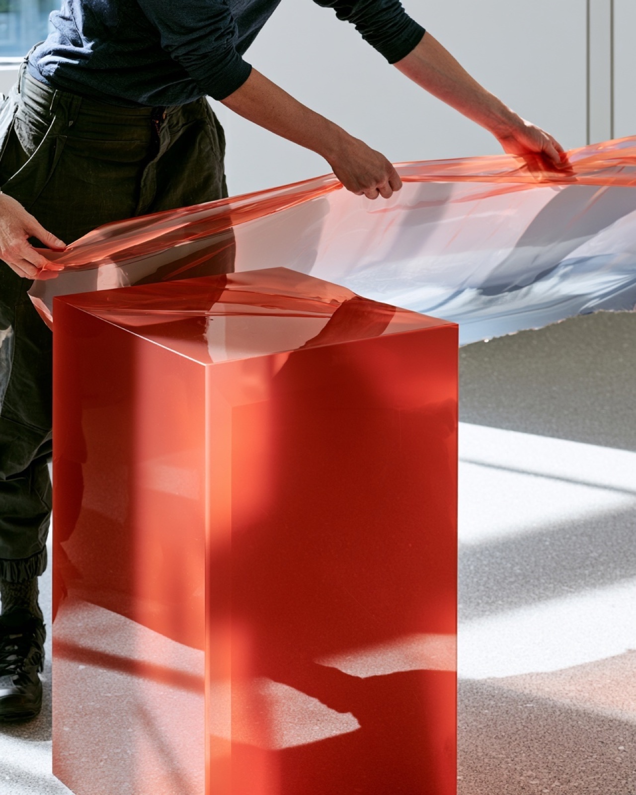 Étude visuelle éditoriale de mains manipulant un objet rouge translucide.