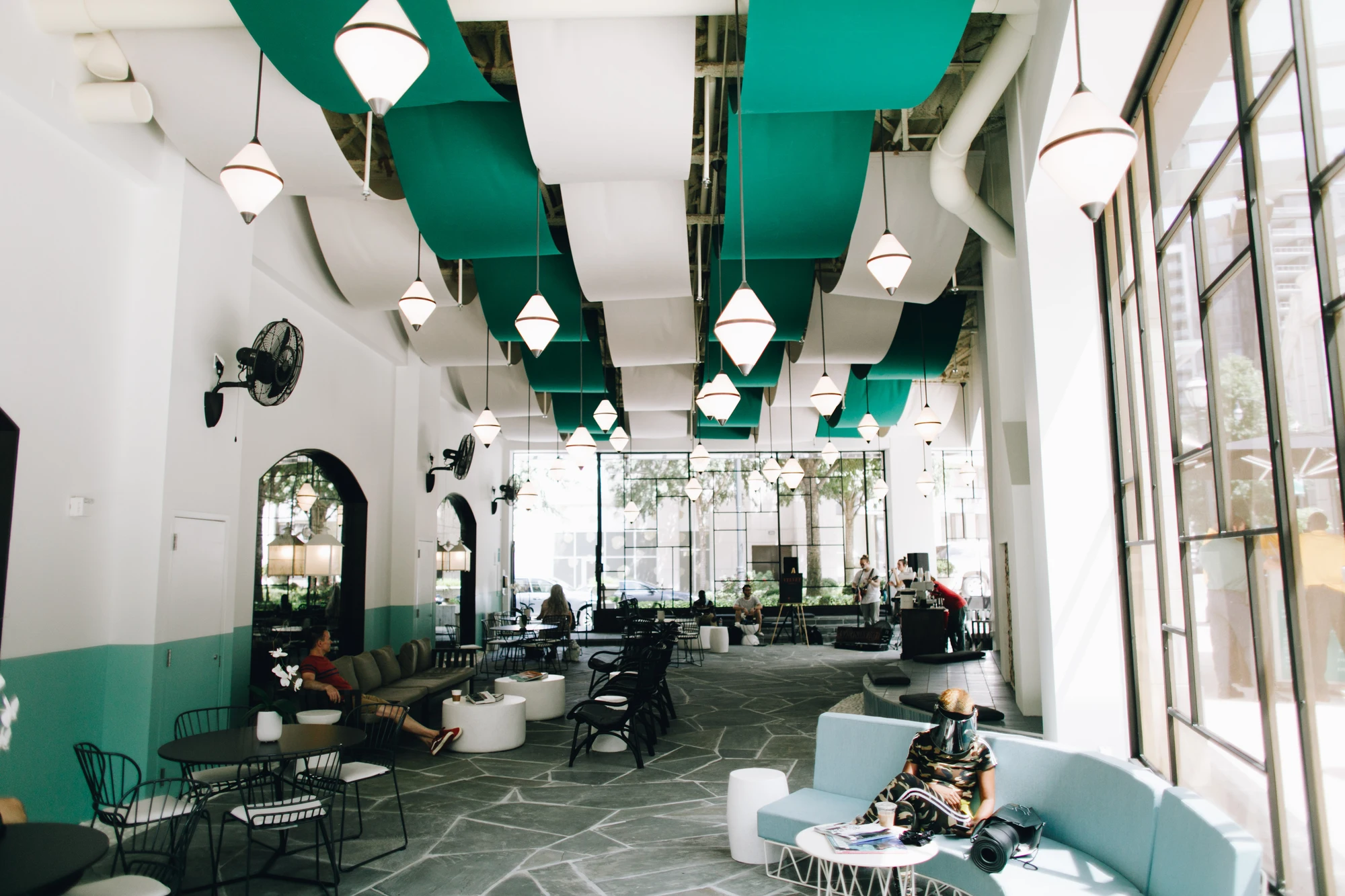 Un intérieur lumineux avec un plafond vert et des suspensions sculpturales.