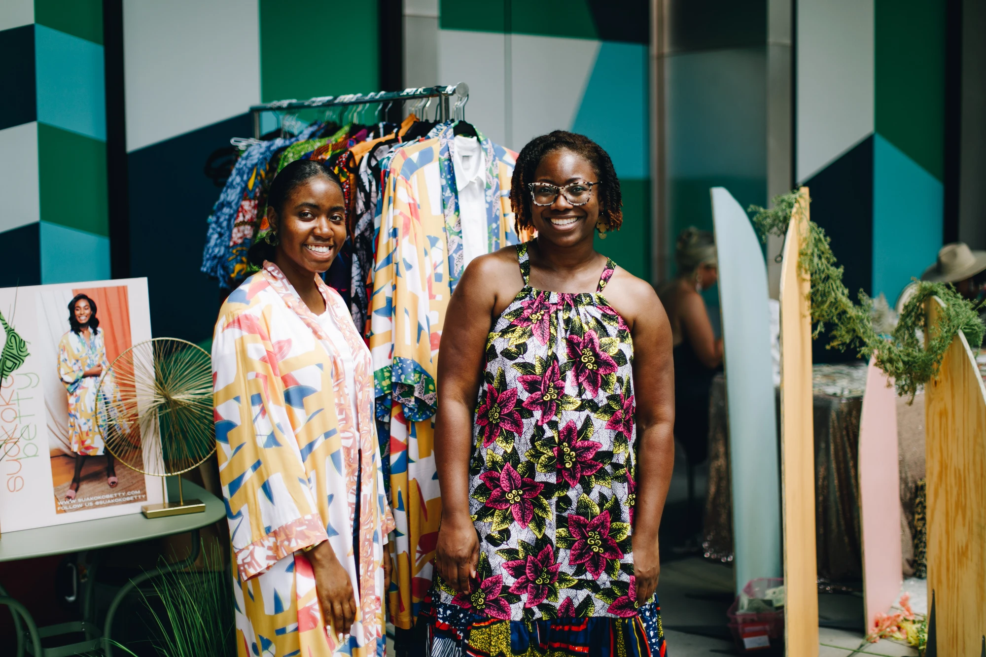 Deux personnes près d’une présentation de vêtements colorés lors d’un événement commercial