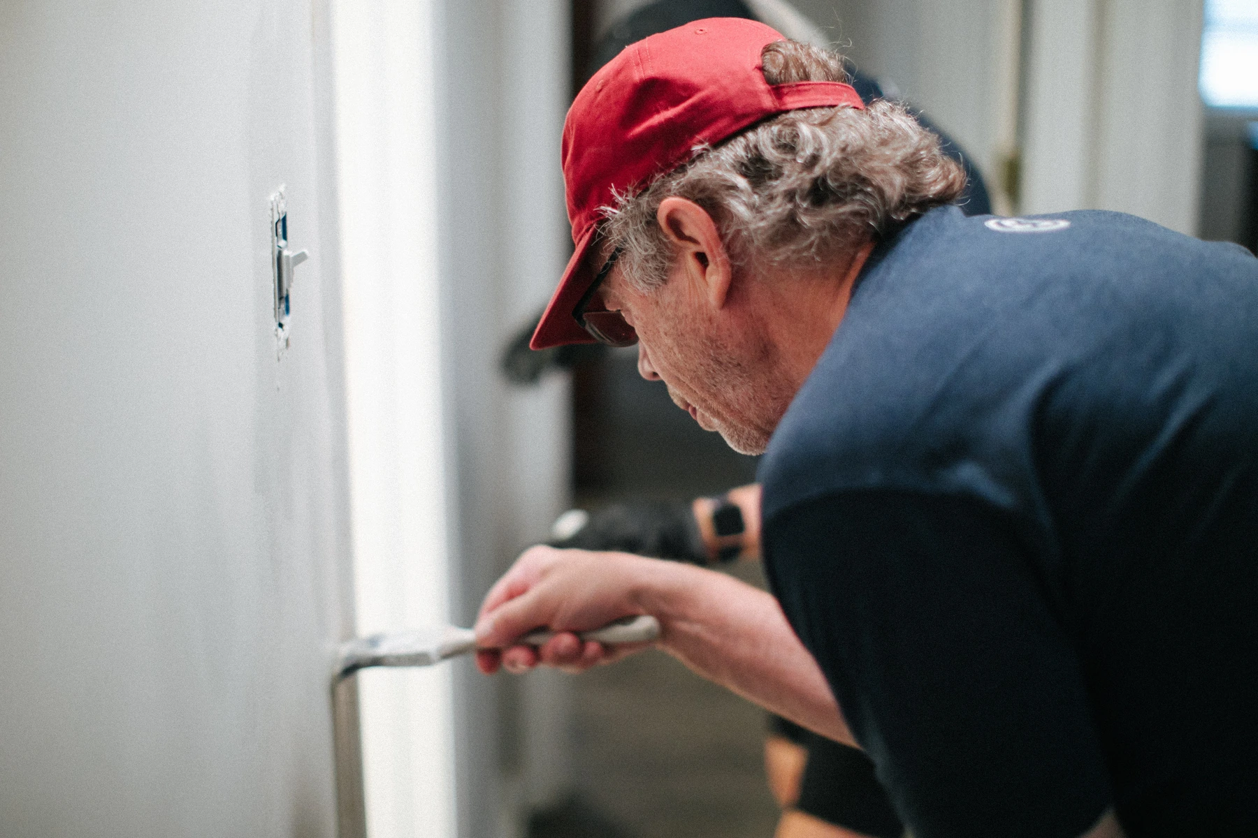 Une personne bénévole peint un mur intérieur lors d’un projet communautaire de Homestretch.