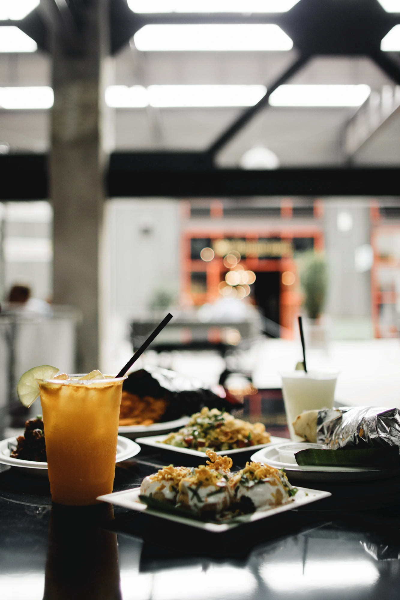 Una mesa de restaurante con platos y una bebida junto a una ventana.