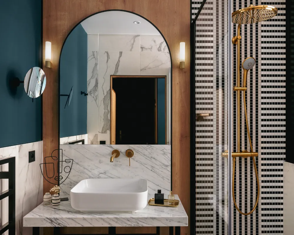 Salle de bain en marbre et bois avec miroir arqué, double vasque et douche vitrée à mosaïque noire et blanche