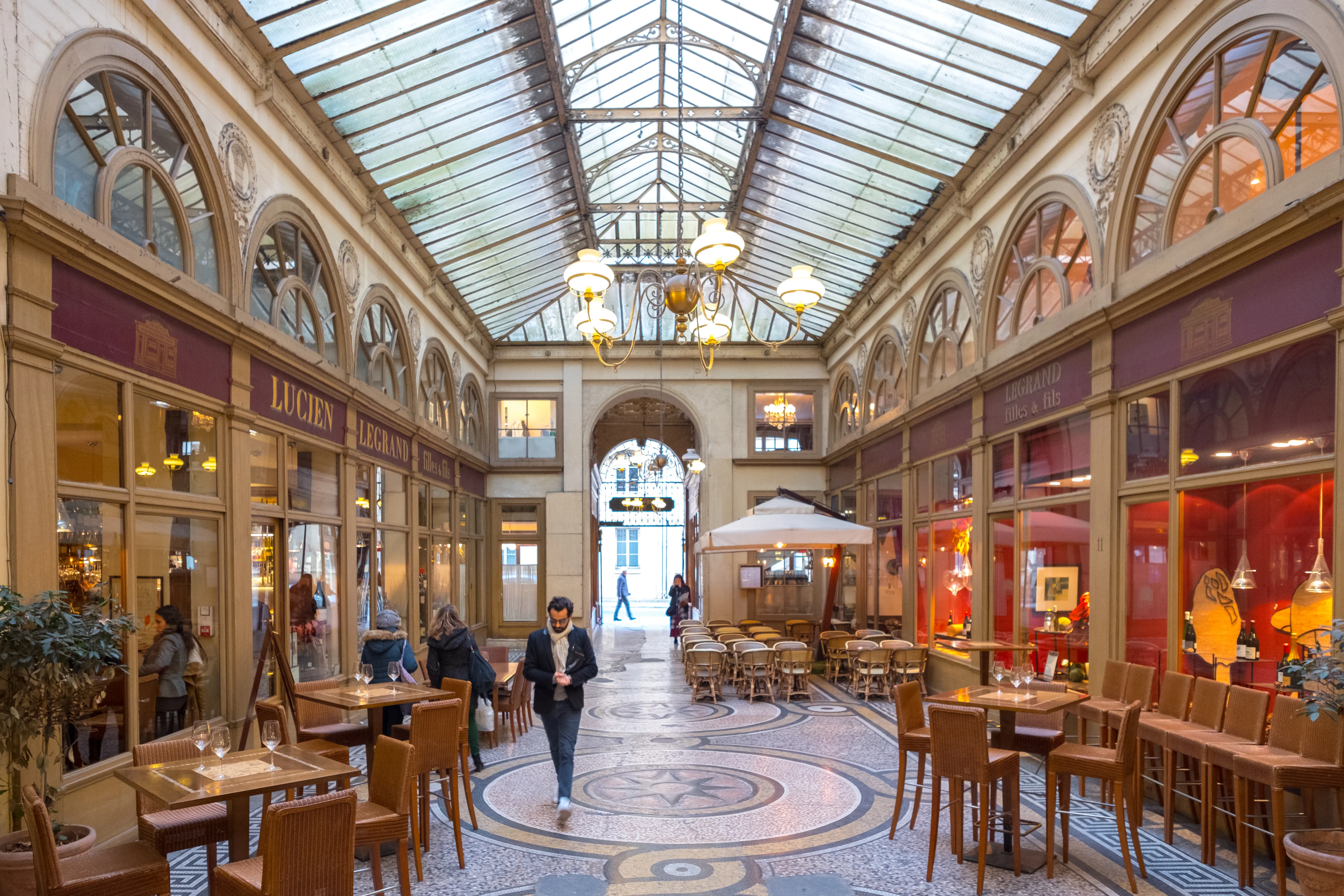 galerie couverte ornée de fresques, verrière lumineuse et boutiques bordant le sol en mosaïque
