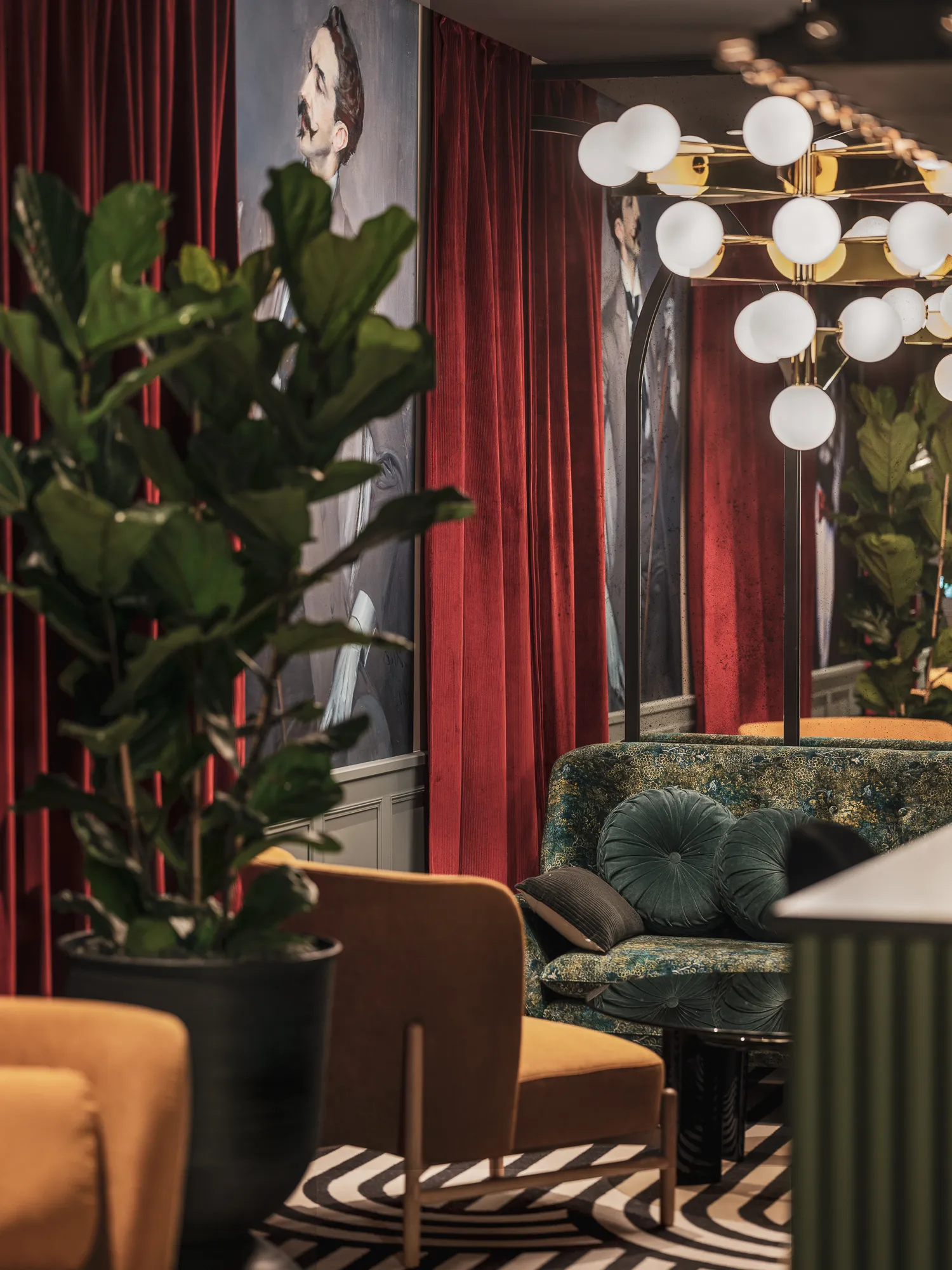 Salon lounge aux rideaux bordeaux et portraits peints, canapé en velours brodé, fauteuils moutarde et lustre à globes suspendus