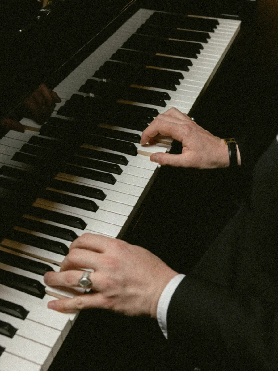 Les mains de Monsieur Charles jouant du piano à queue lors d'une soirée musicale à l'Hôtel Dandy à Paris.