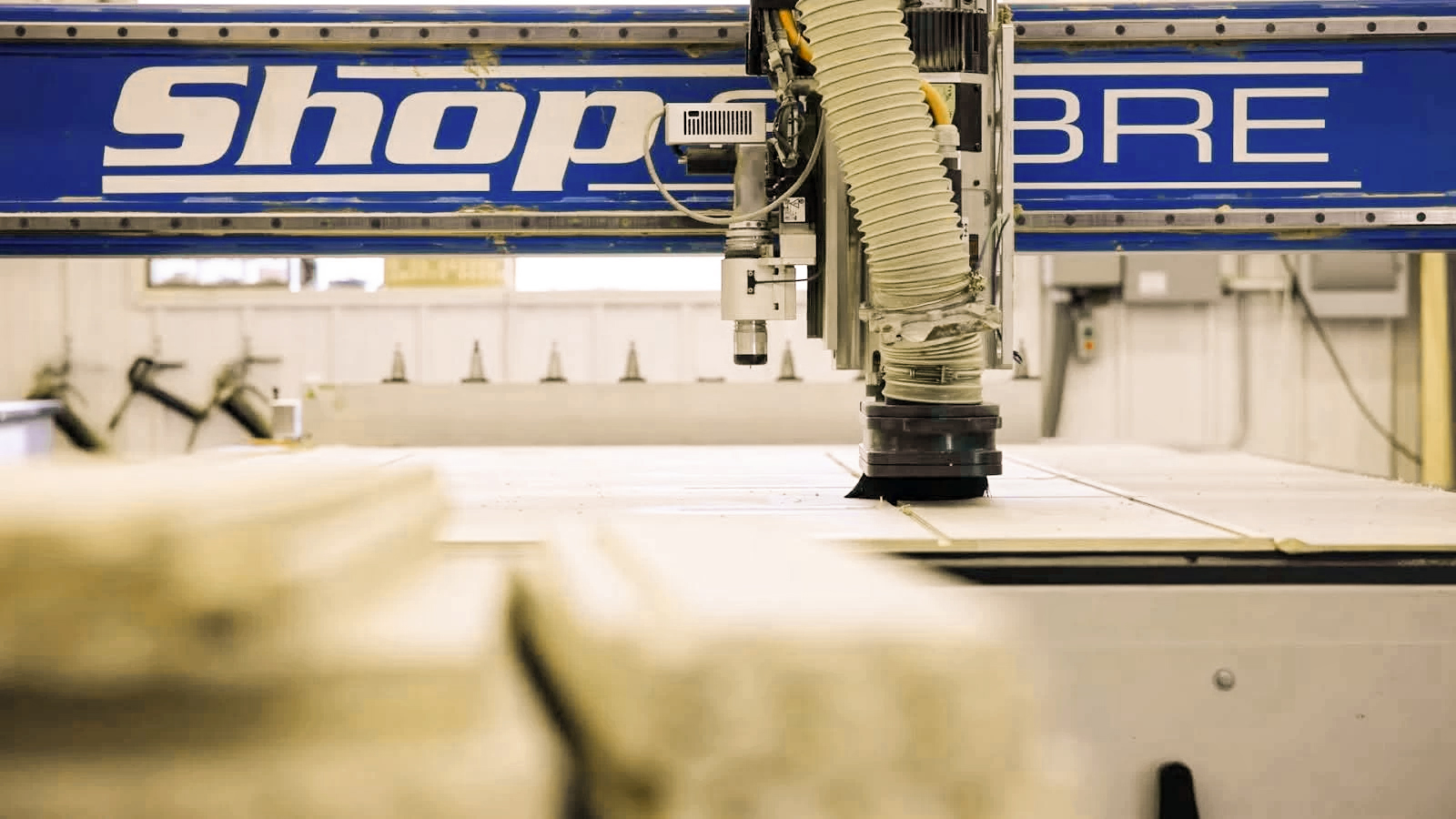 Close-up of ShopSabre CNC machine's cutting tool above a wood surface in a workshop.
