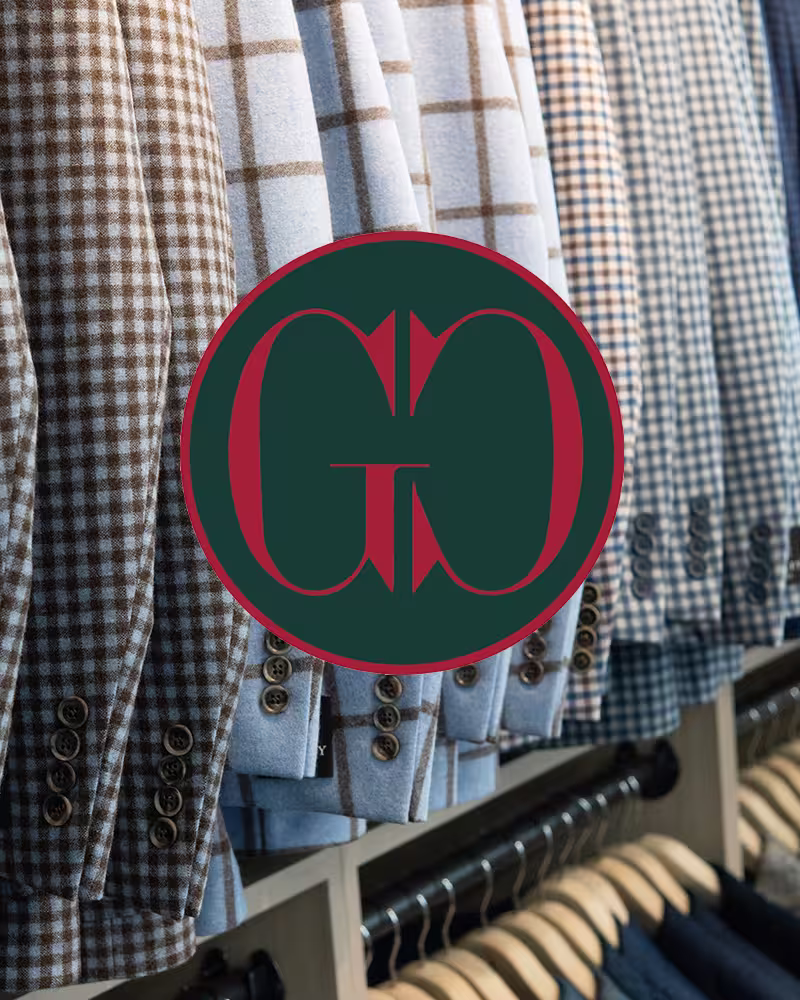Various checked suit jackets hanging on a rack in a clothing store.