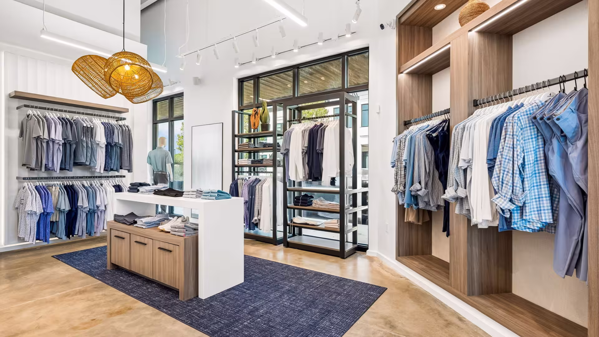 Modern clothing store interior with neatly arranged shirts and pants on racks and shelves.