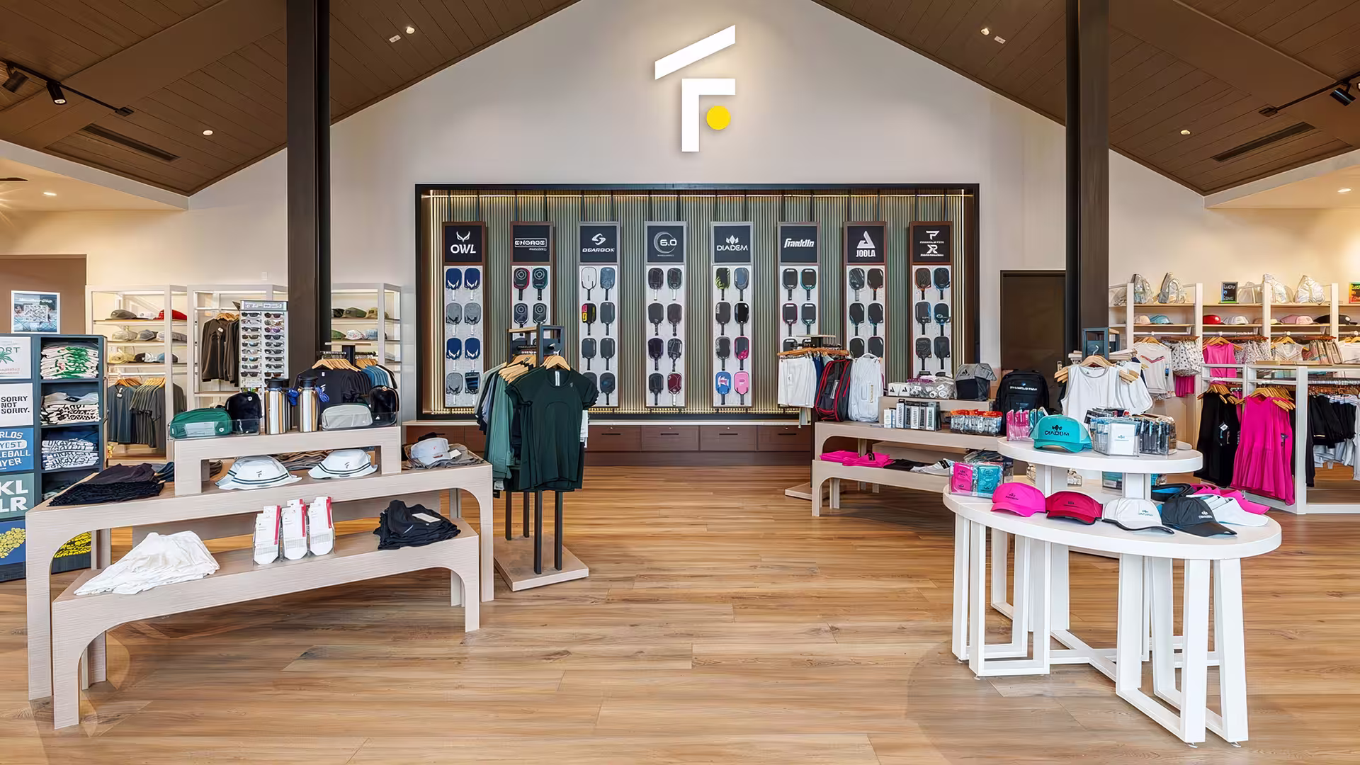 Sports store interior with wooden floors, apparel racks, and wall displays of sports equipment.