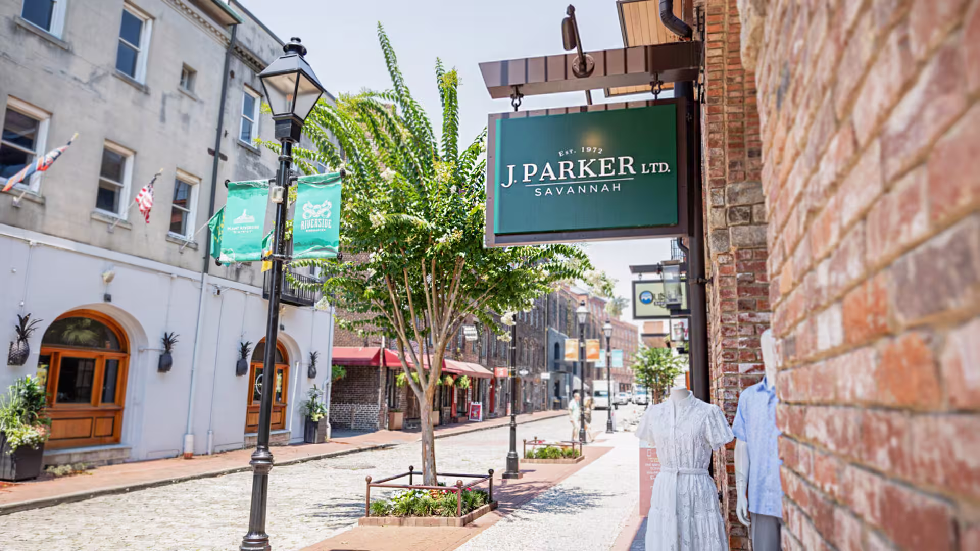 Street view with a green J. Parker Ltd. Savannah sign and mannequins dressed in summer clothing.