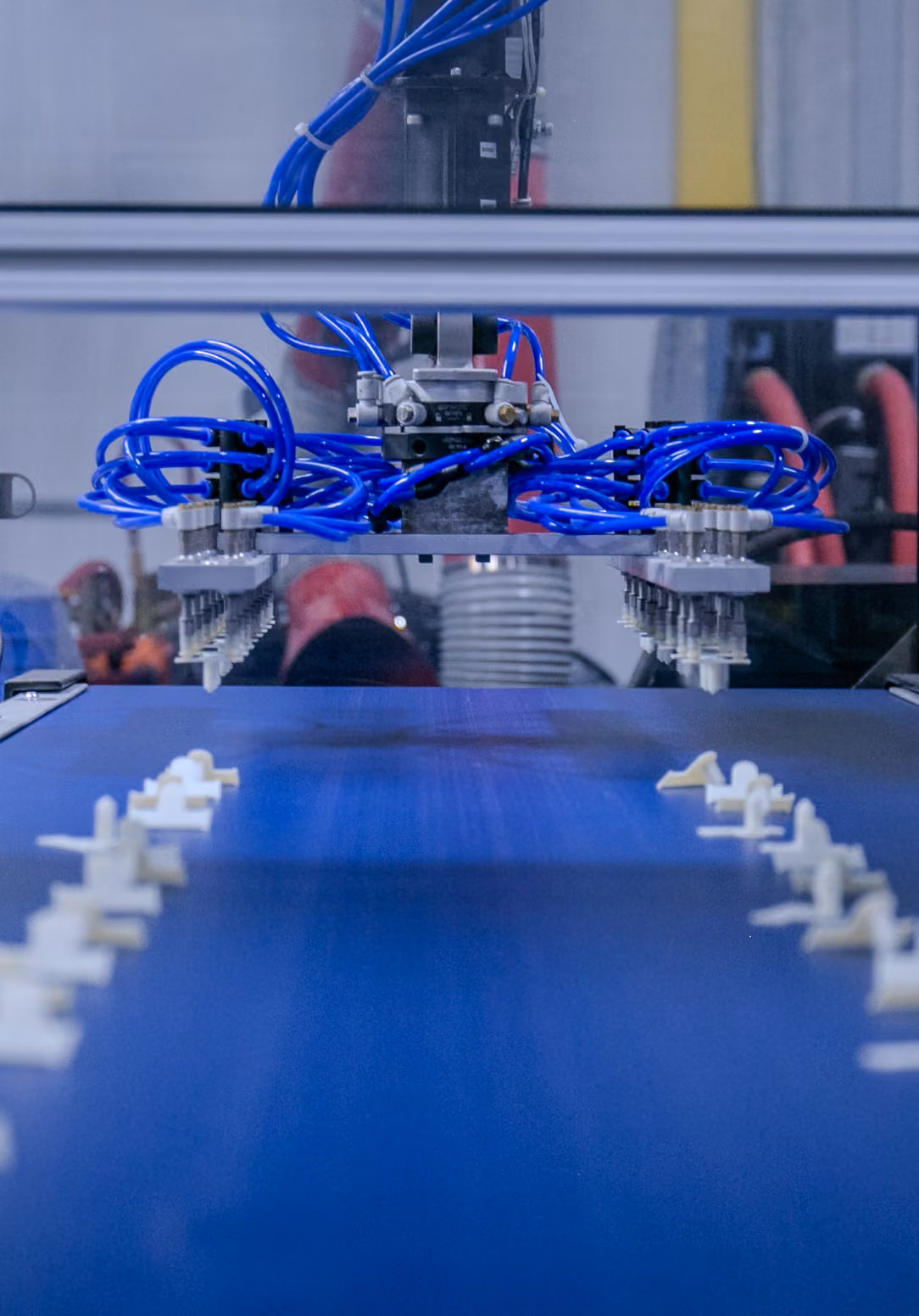 Robotic arm with pneumatic gripper picking small molded parts from a conveyor