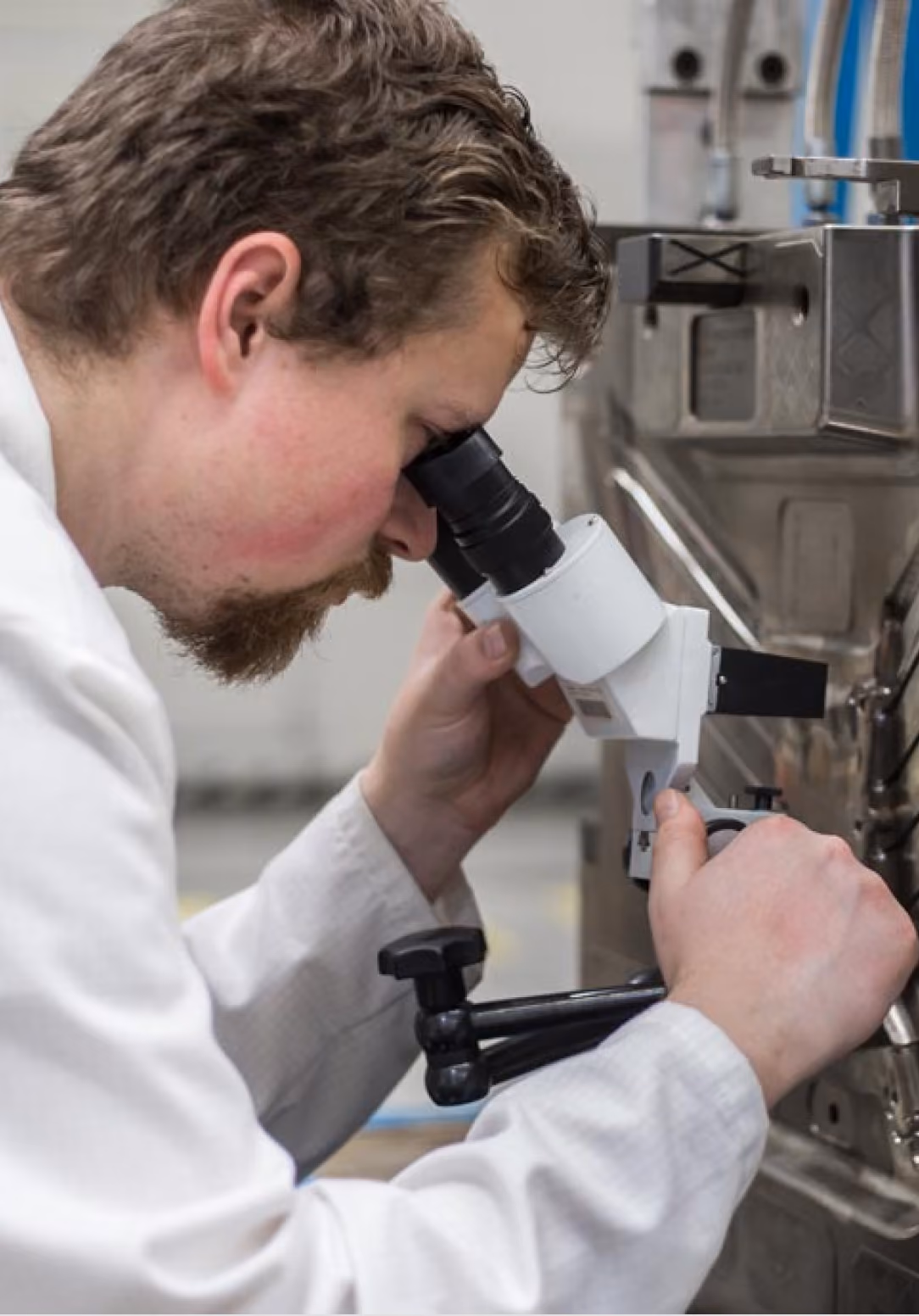 Quality inspector examining a part through a microscope in a clean room