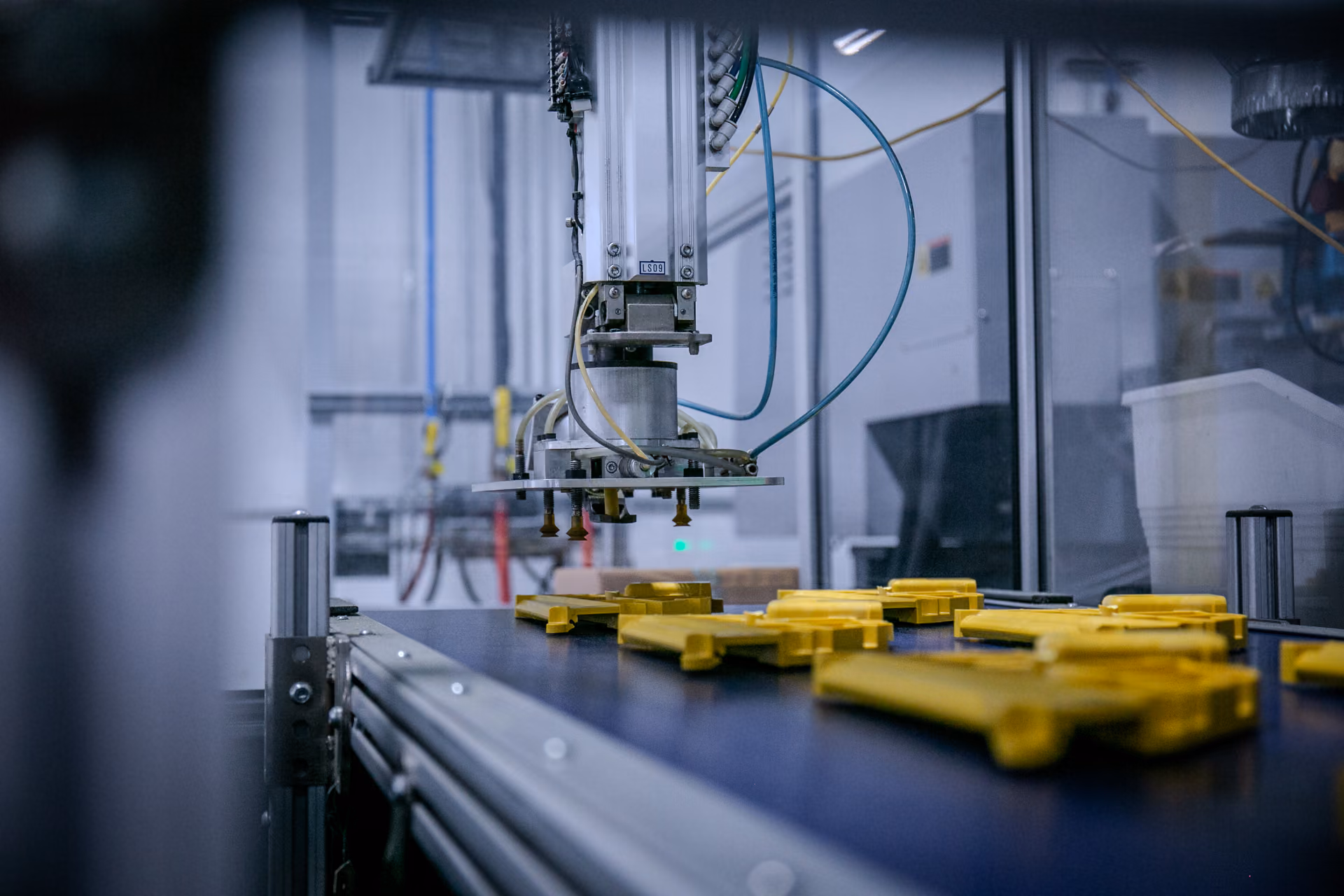 Automated gripper placing molded yellow parts onto a conveyor