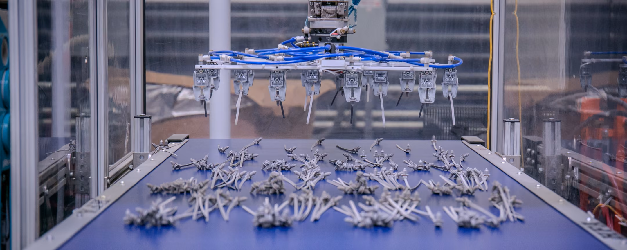 Automated gripper placing molded yellow parts onto a conveyor
