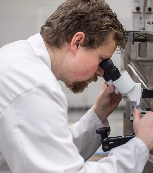 Uniphase engineer inspecting a molded part under a microscope