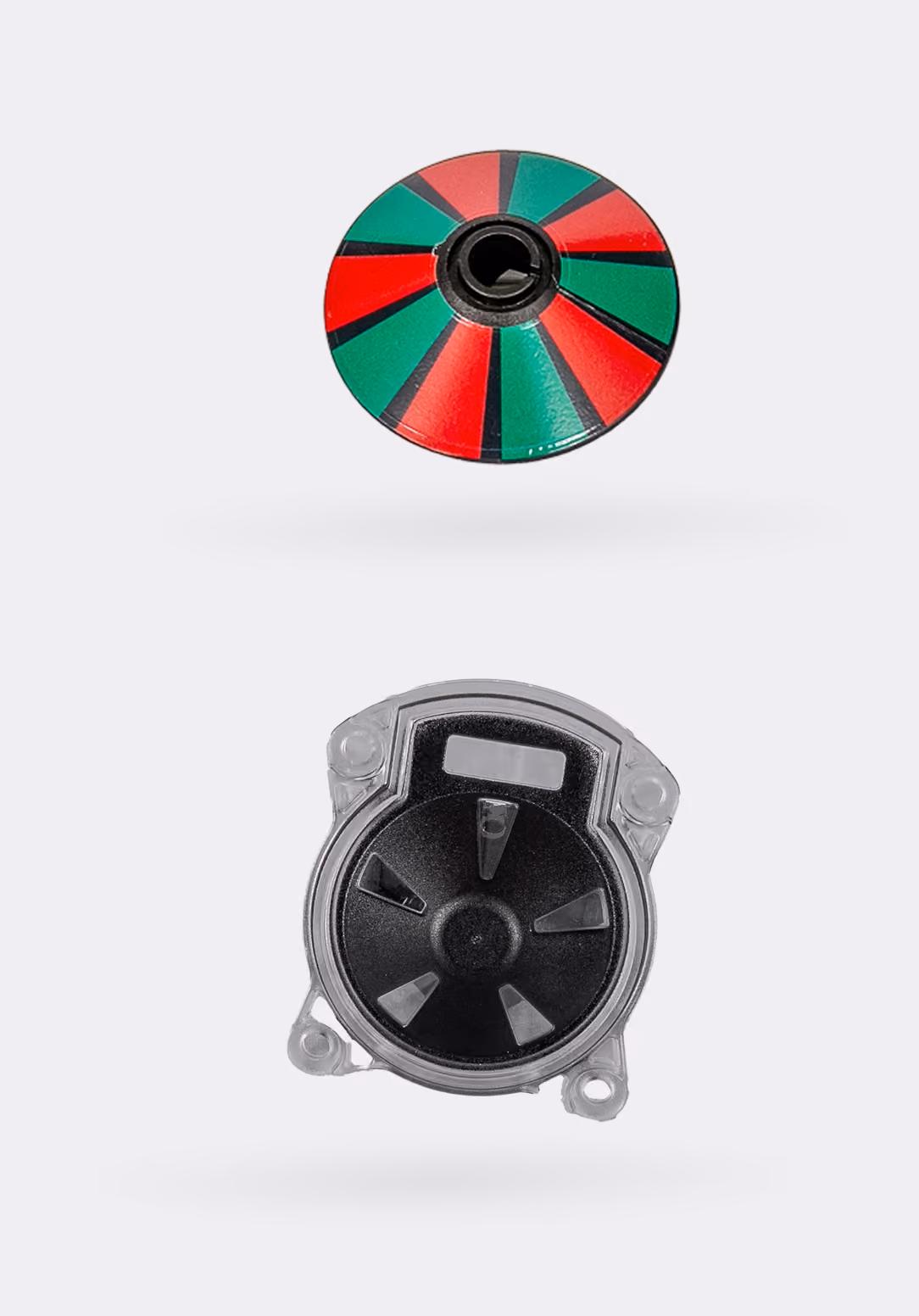 Red and green industrial sensor wheel component above a molded plastic sensor housing, used in industrial manufacturing