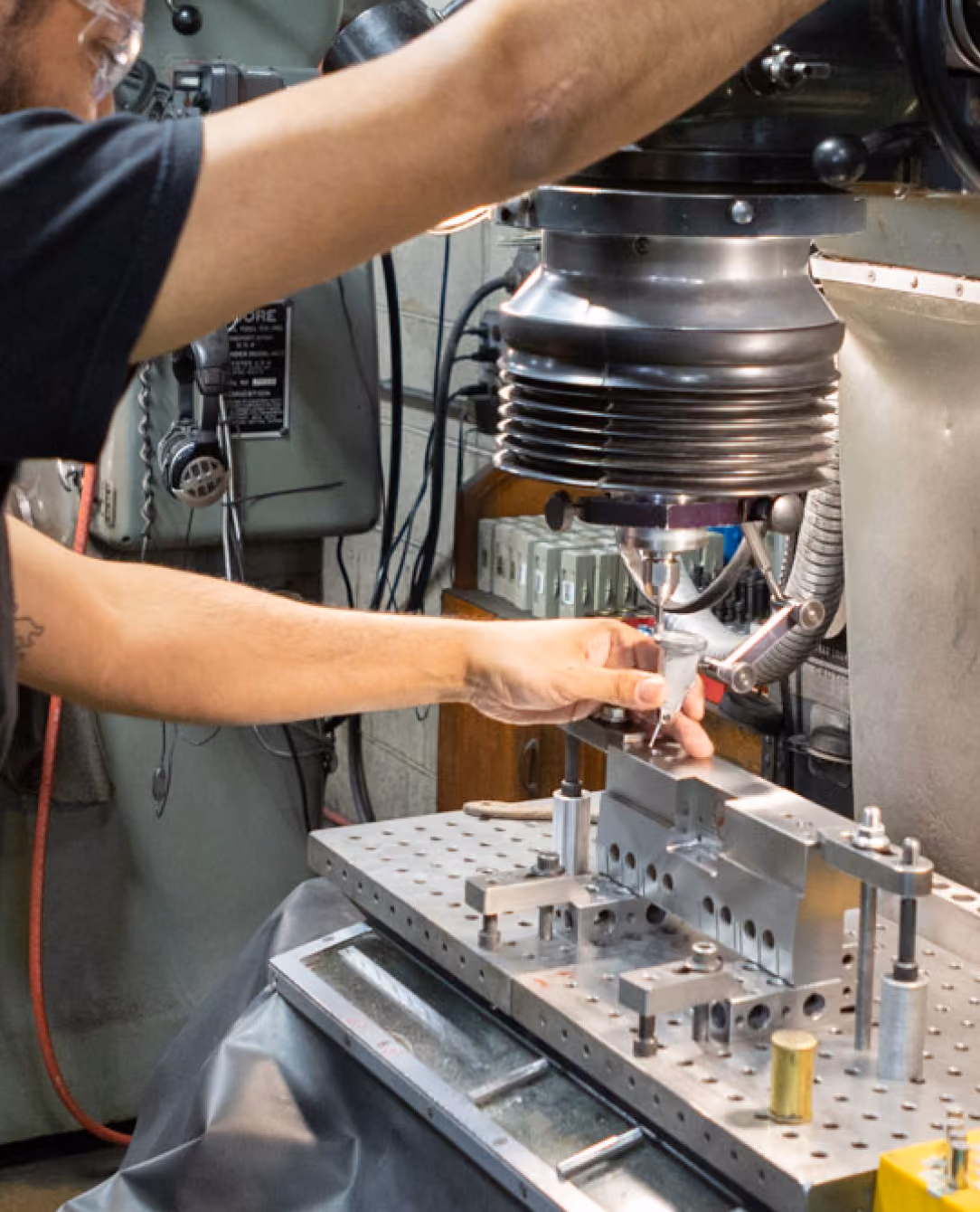 Technician operating a precision milling machine on a metal fixture plate