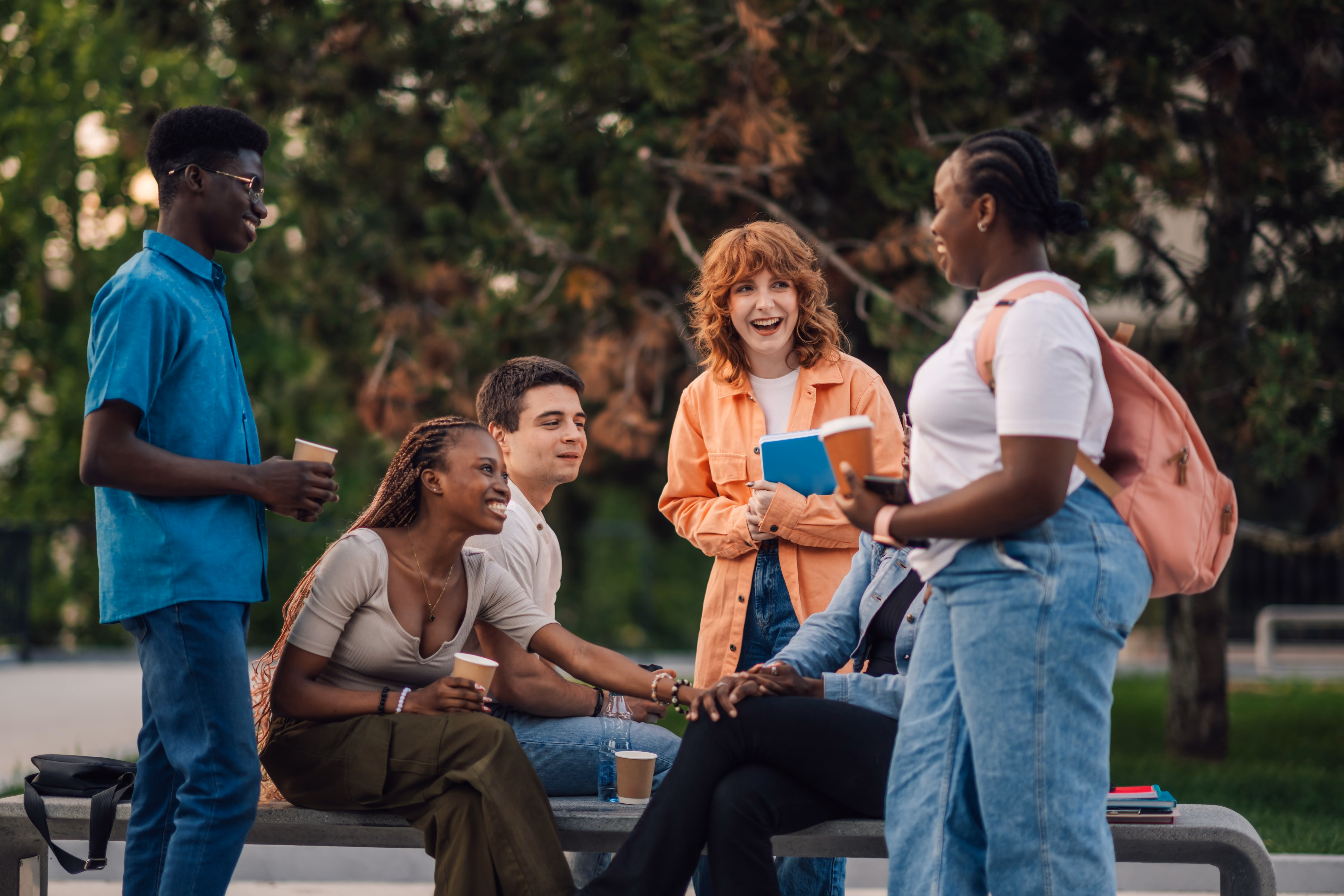 People with backpacks on talking on bench stock image