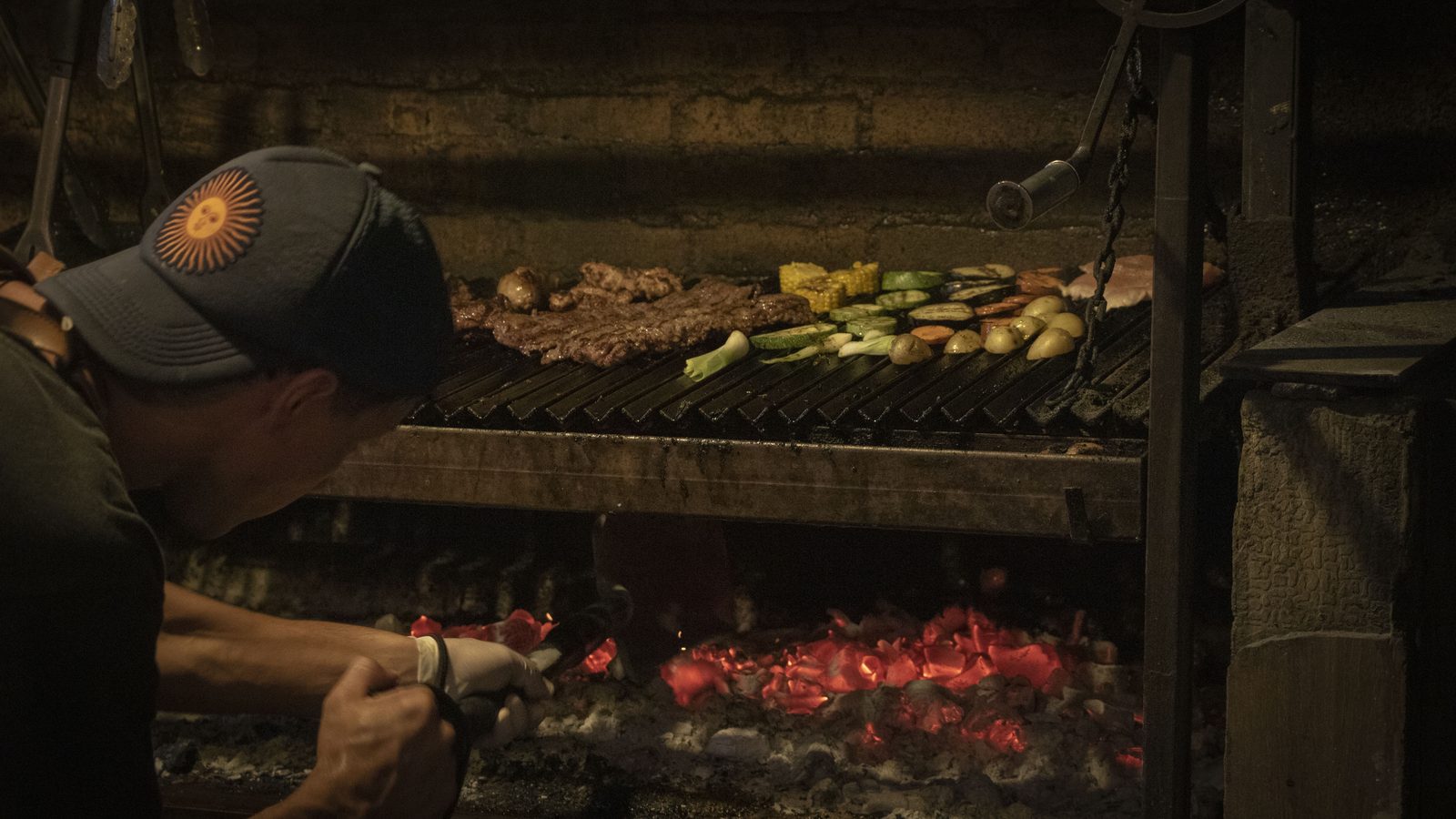 Parrillero acomodando carbón encendido en Fuego Santo, parrilla en Playa del Carmen
