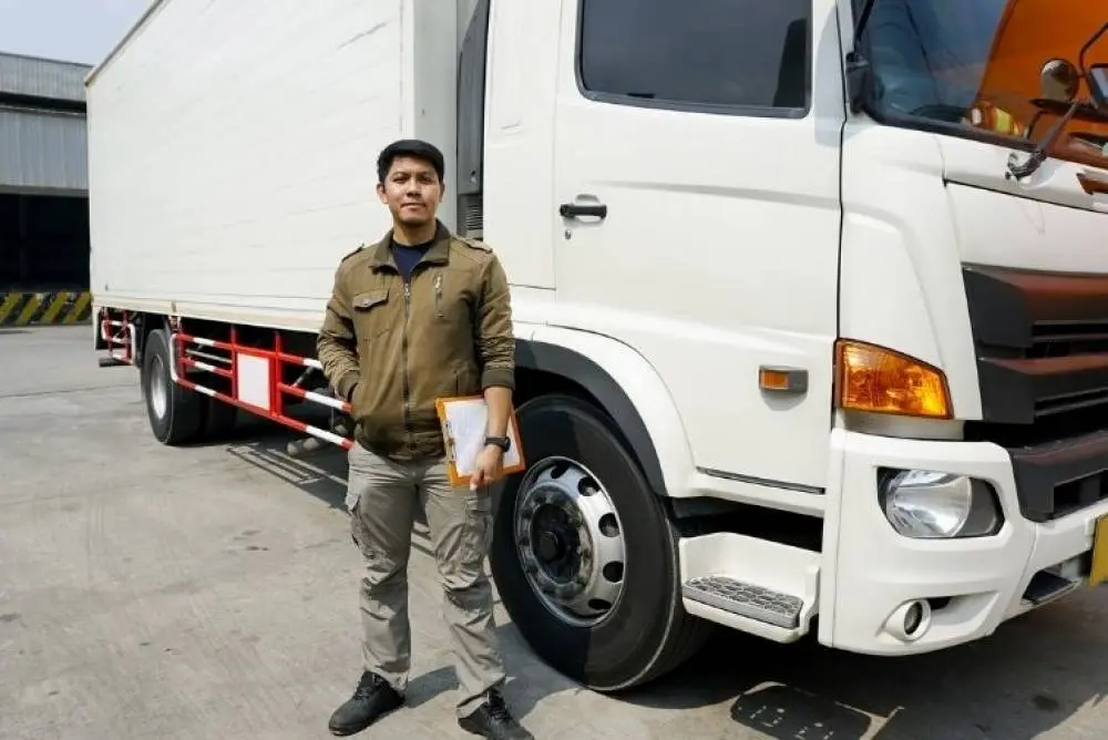 Driver standing in front of their vehicle, holding a checklist