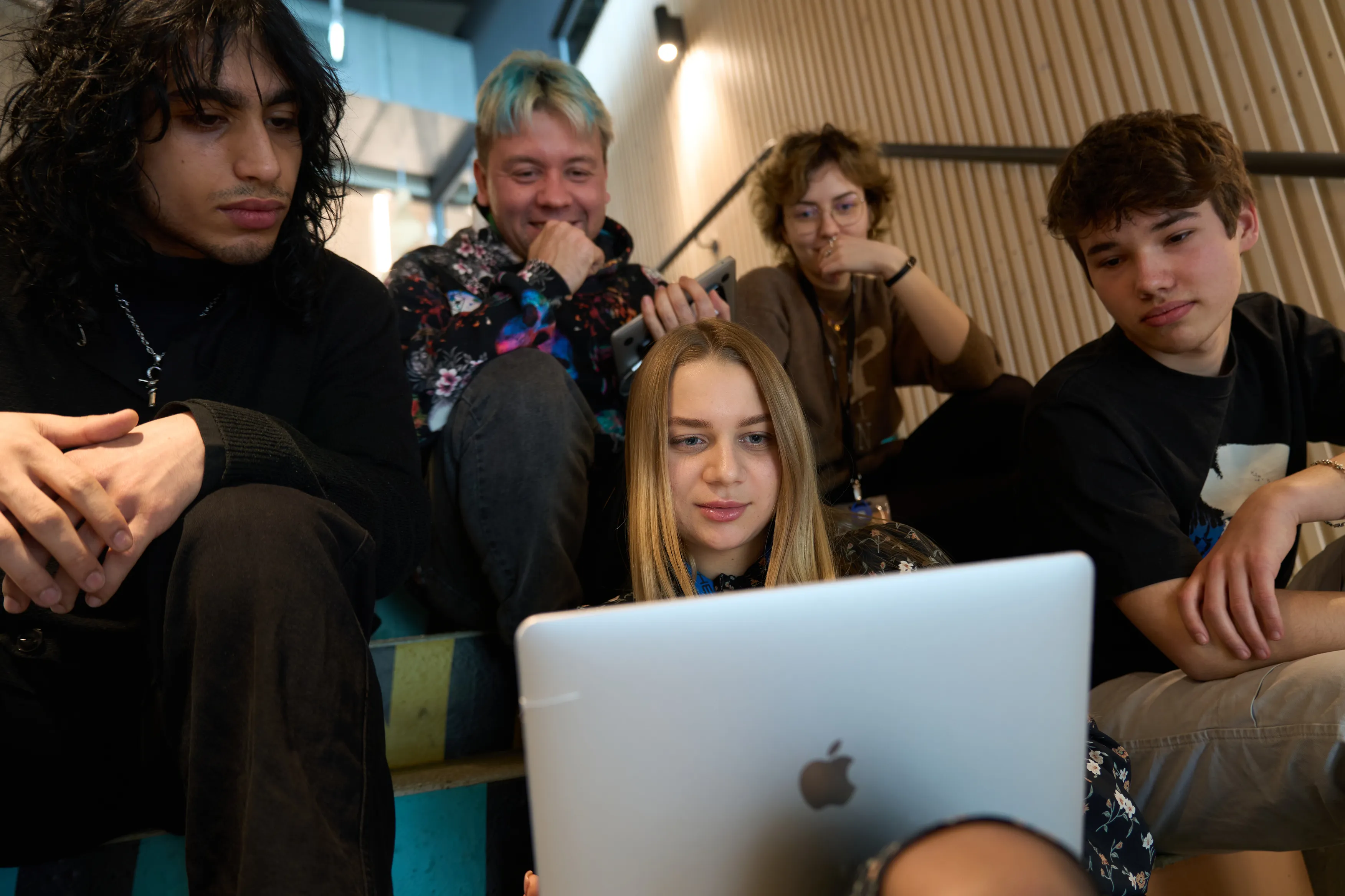 Students gathered around a laptop on the bleachers