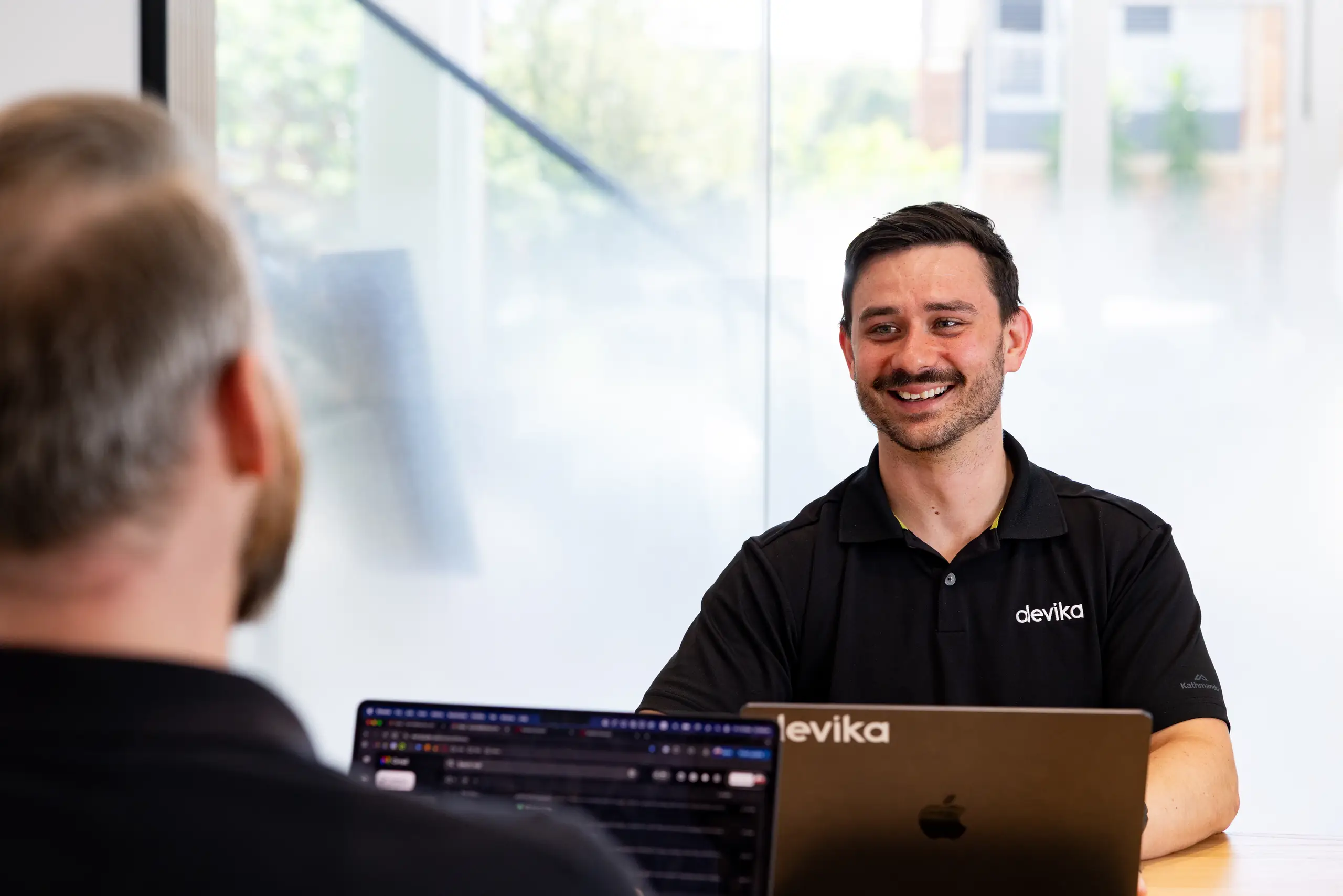 Two Devika team members collaborating across a meeting table
