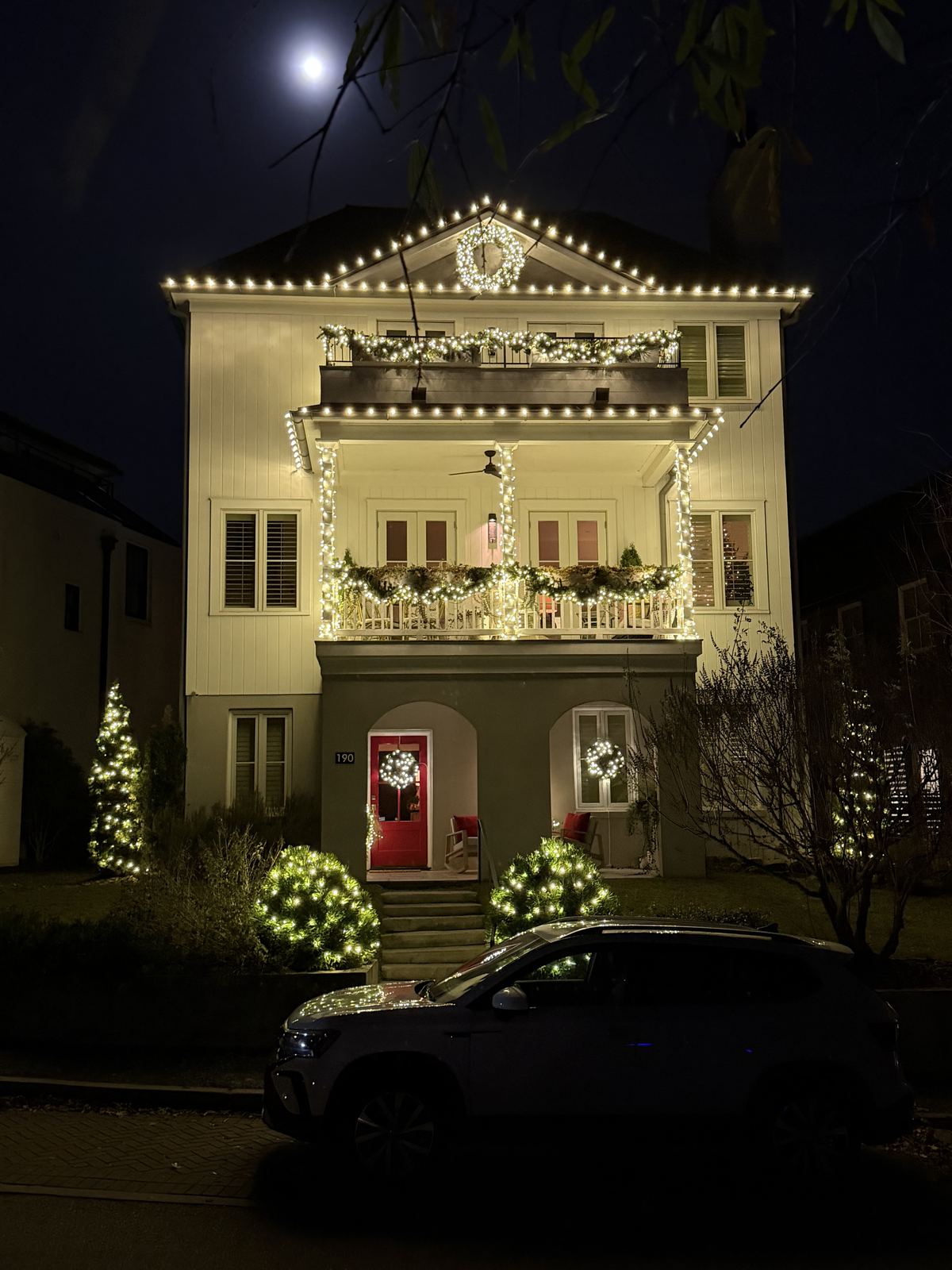 Brick home with roofline lights and glowing garland under a full moon