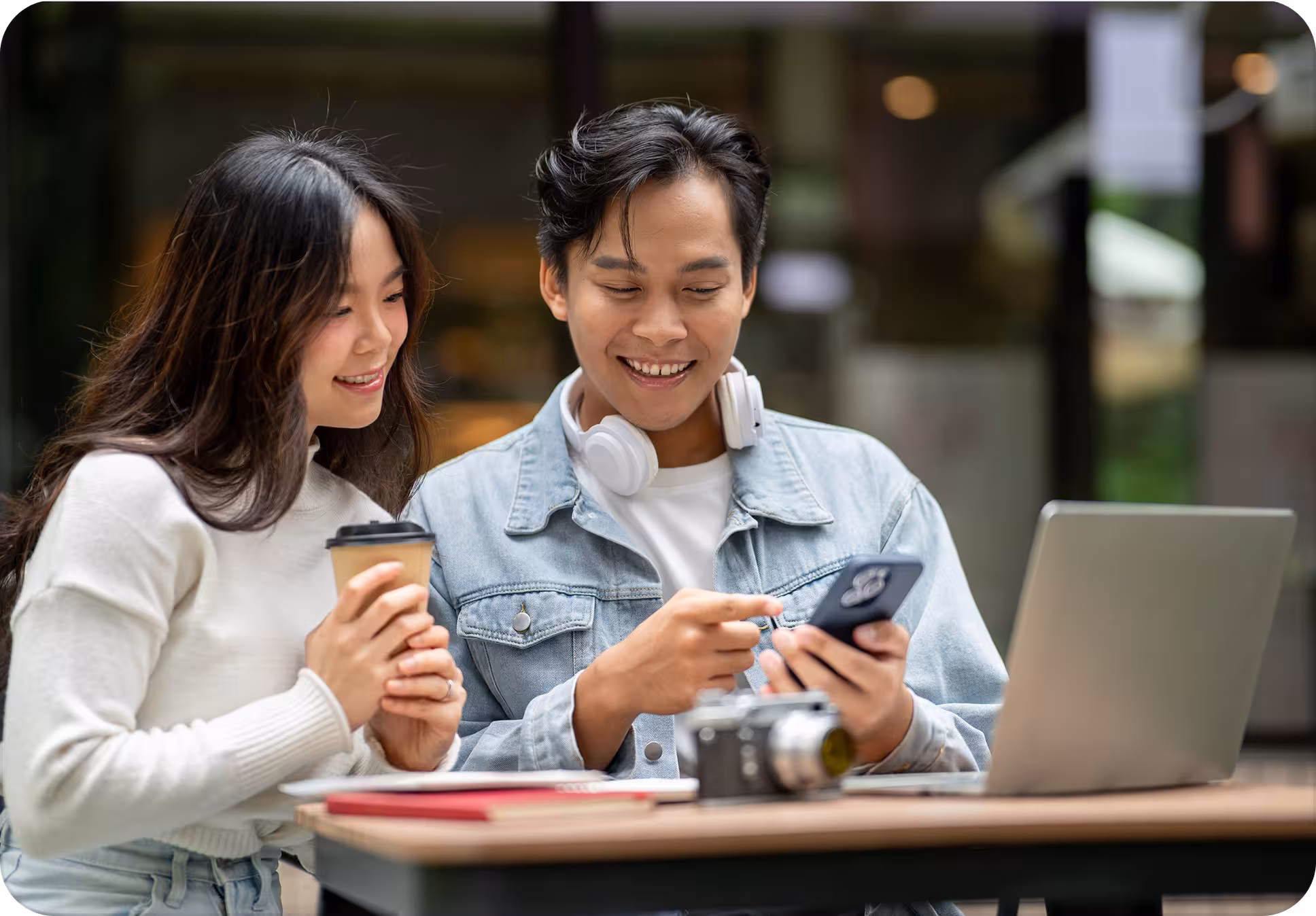 Young couple checking loan options together on a phone at a cafe