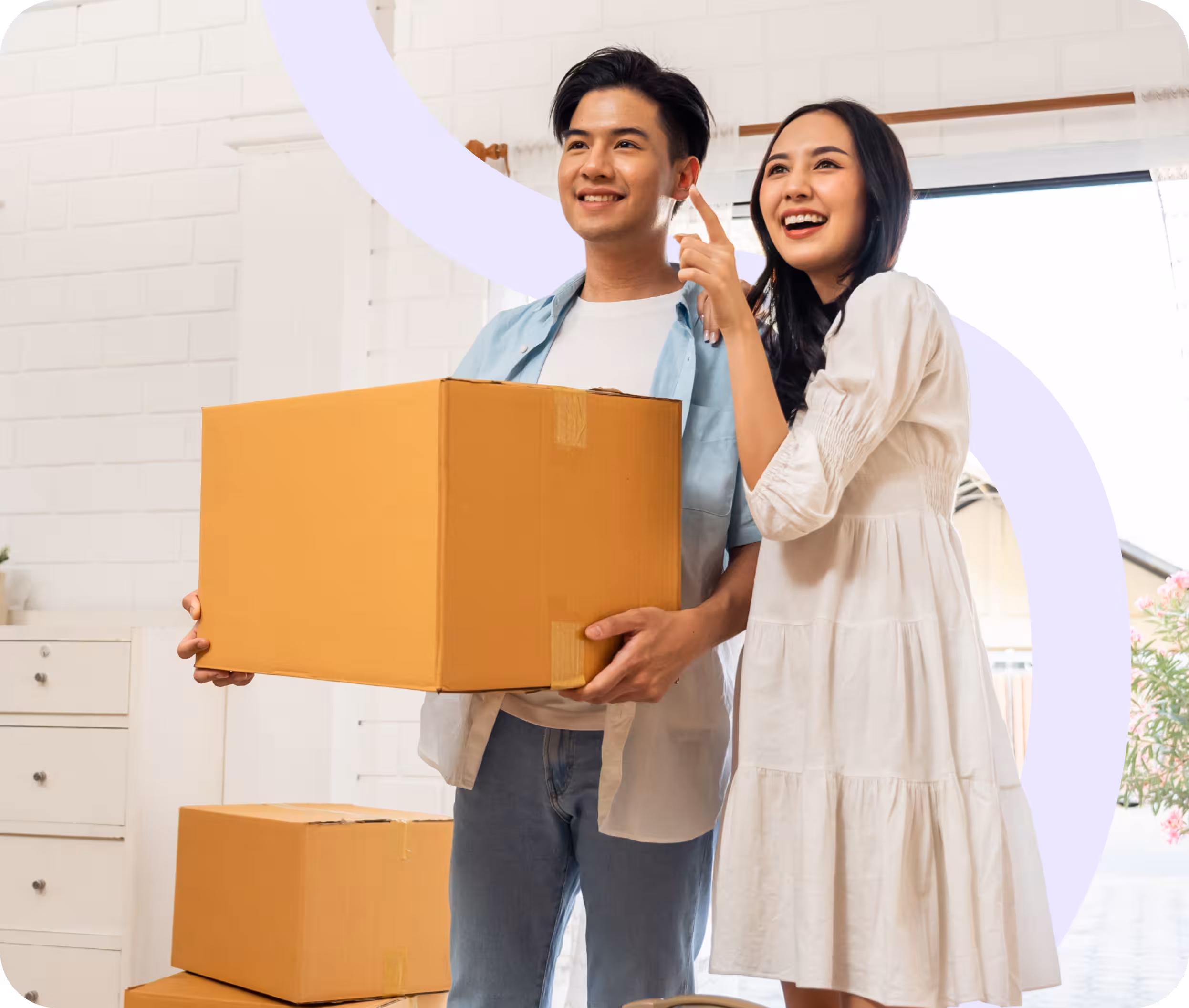Couple holding moving boxes in front of their new home