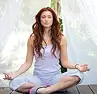 Woman with long red hair meditating cross-legged in a calm indoor space