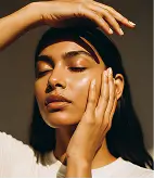 Woman with closed eyes posing with one hand on face and the other above her forehead.