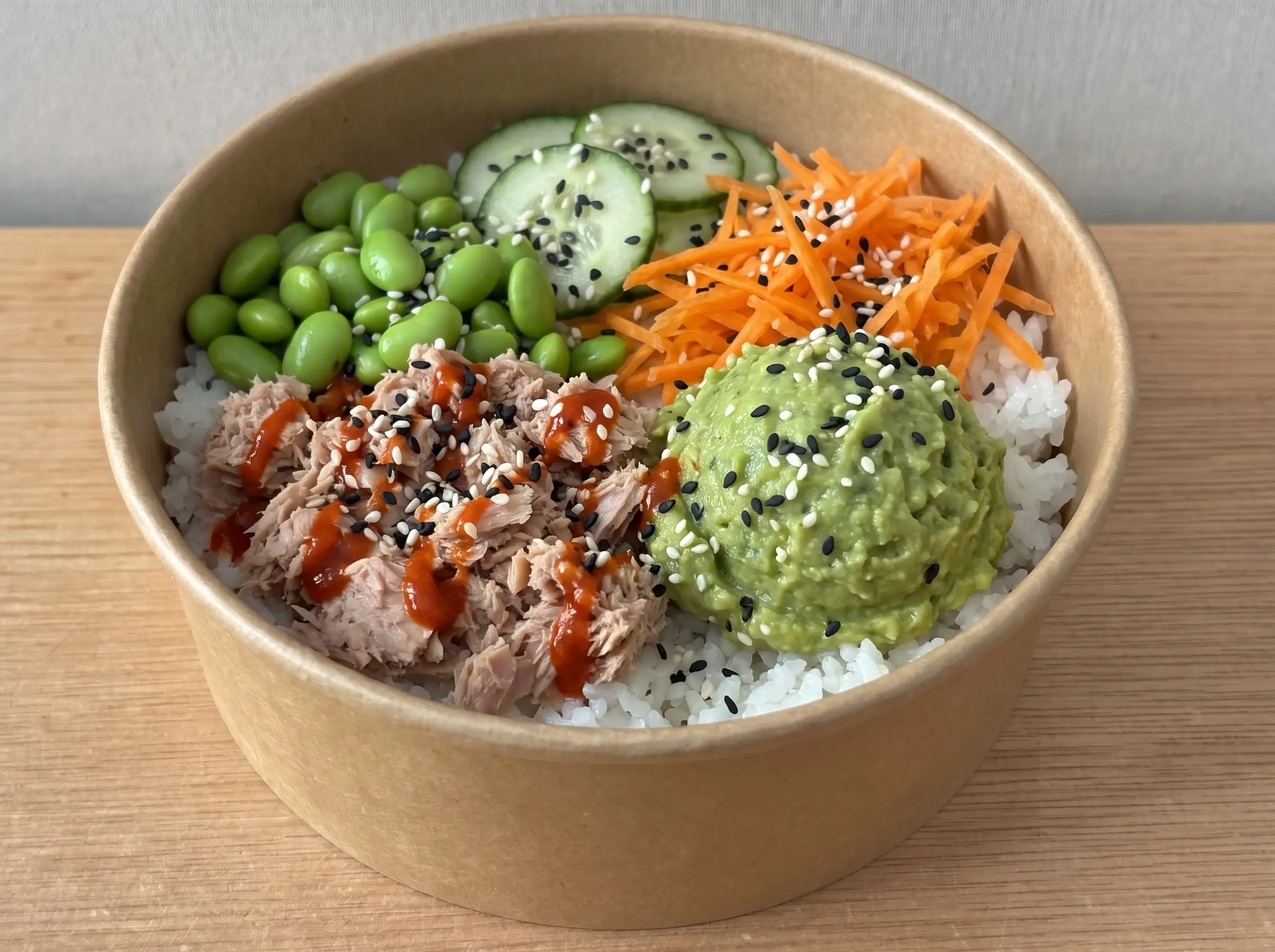 Poke Classic in brauner Pappschale: Thunfisch in Sriracha-Soße, Sushireis, Edamame, Möhren, Gurke und Guacamole