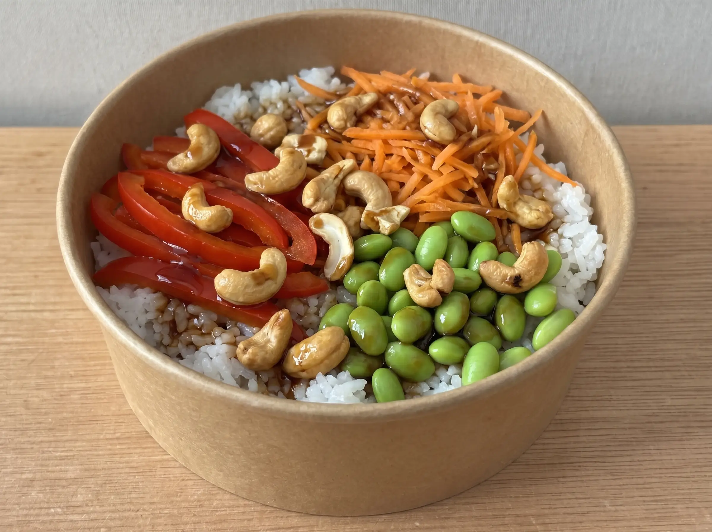 Cashew Veggie Teriyaki in brauner Pappschale: Sushireis, Paprika, Möhren, Edamame, Teriyaki-Glasur und geröstete Cashews