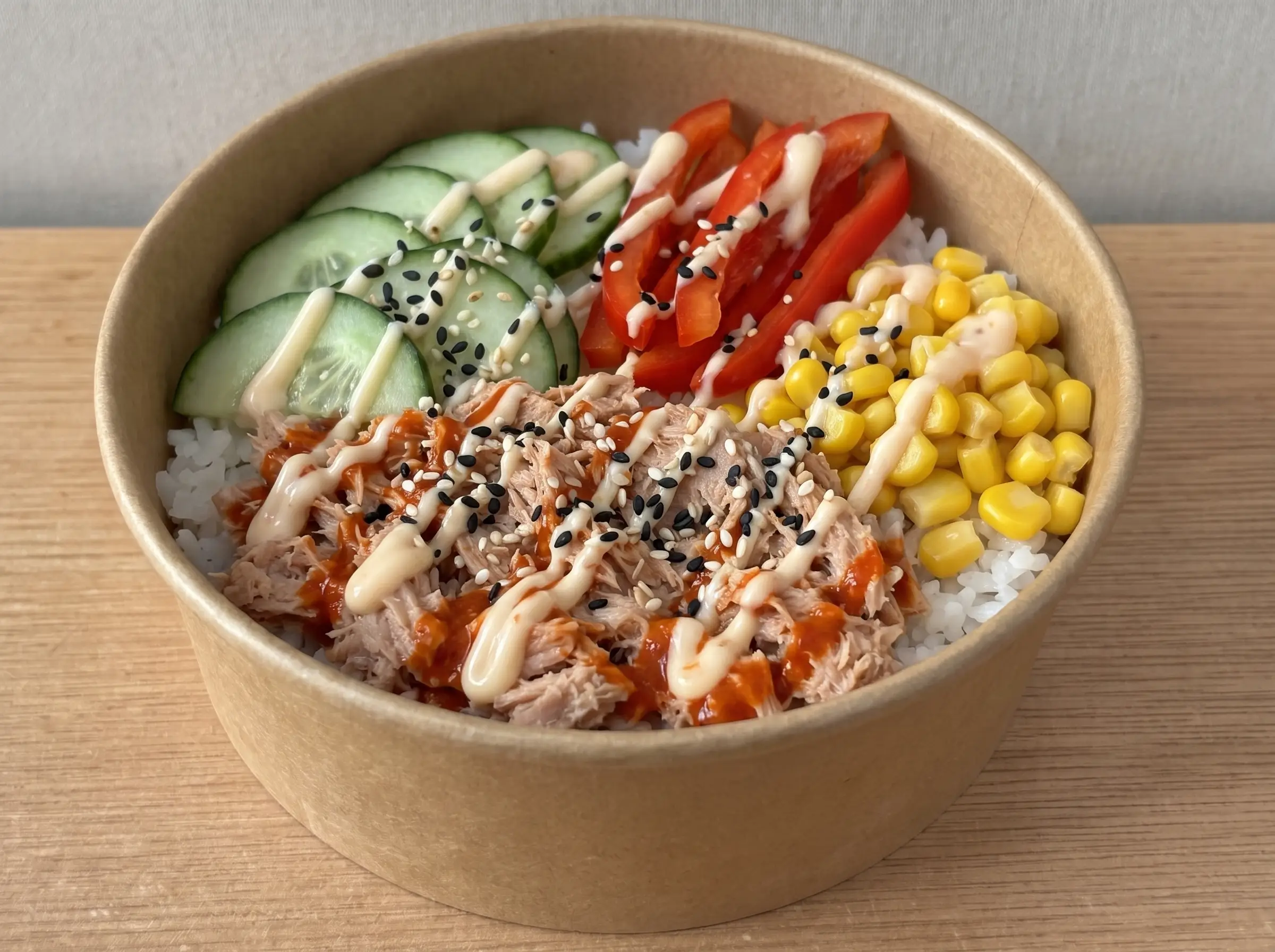 Spicy Tuna Bowl in brauner Pappschale: Thunfisch in Sriracha-Soße, Sushireis, Gurke, Paprika, Mais und Sweet Chilli Mayo