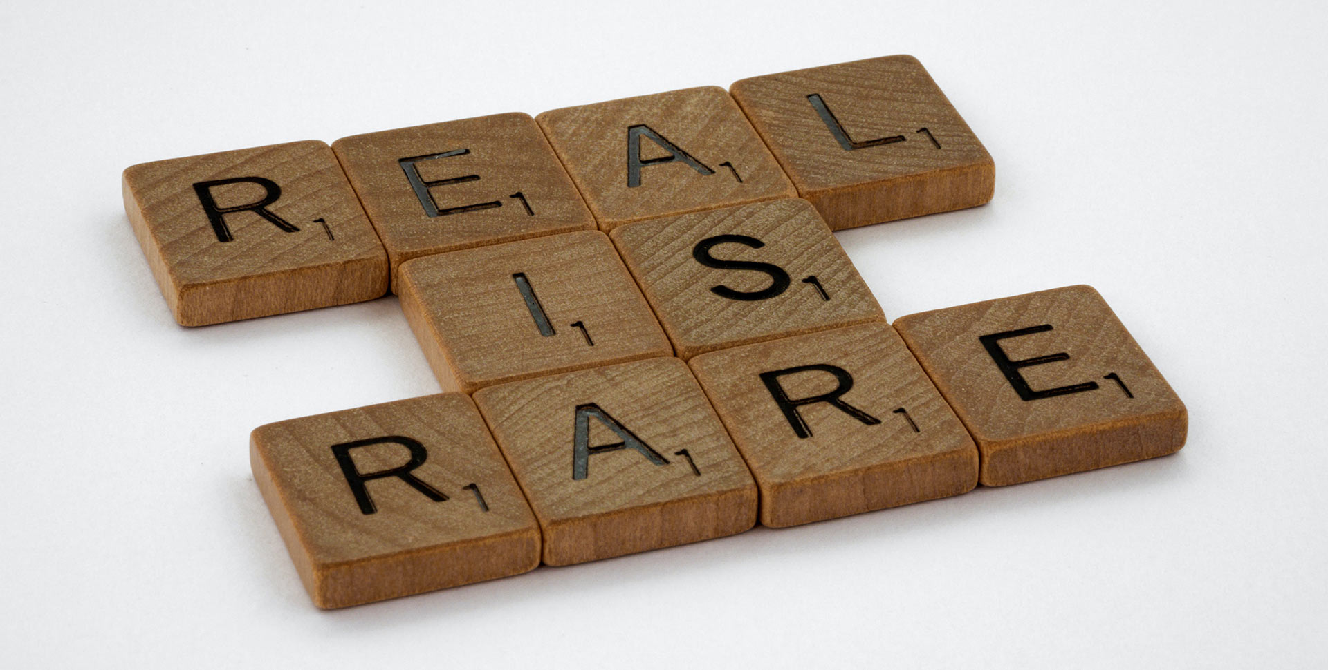 Bild mit kleinen Holzblöcken mit Buchstaben die nebeneinander "Real is Rare" ergeben.