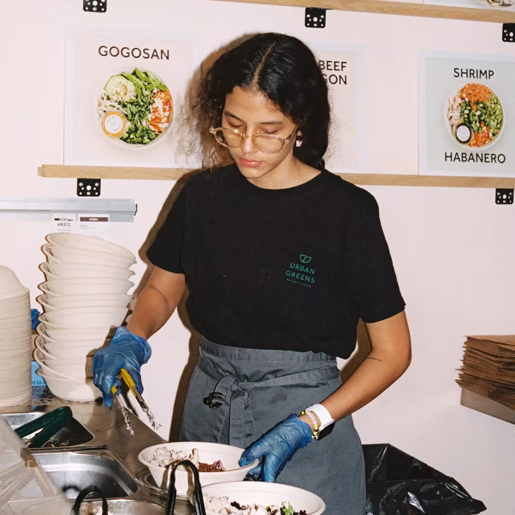 Team member assembling a salad bowl behind the counter.
