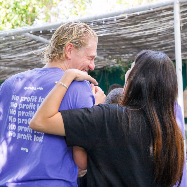 Nory colleagues embracing at an outdoor team event