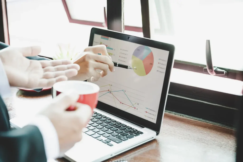 Photo of two people reviewing analytics on a laptop screen with pie charts and line graphs under the heading “How Can Web Analytics Help Optimize Content Design?