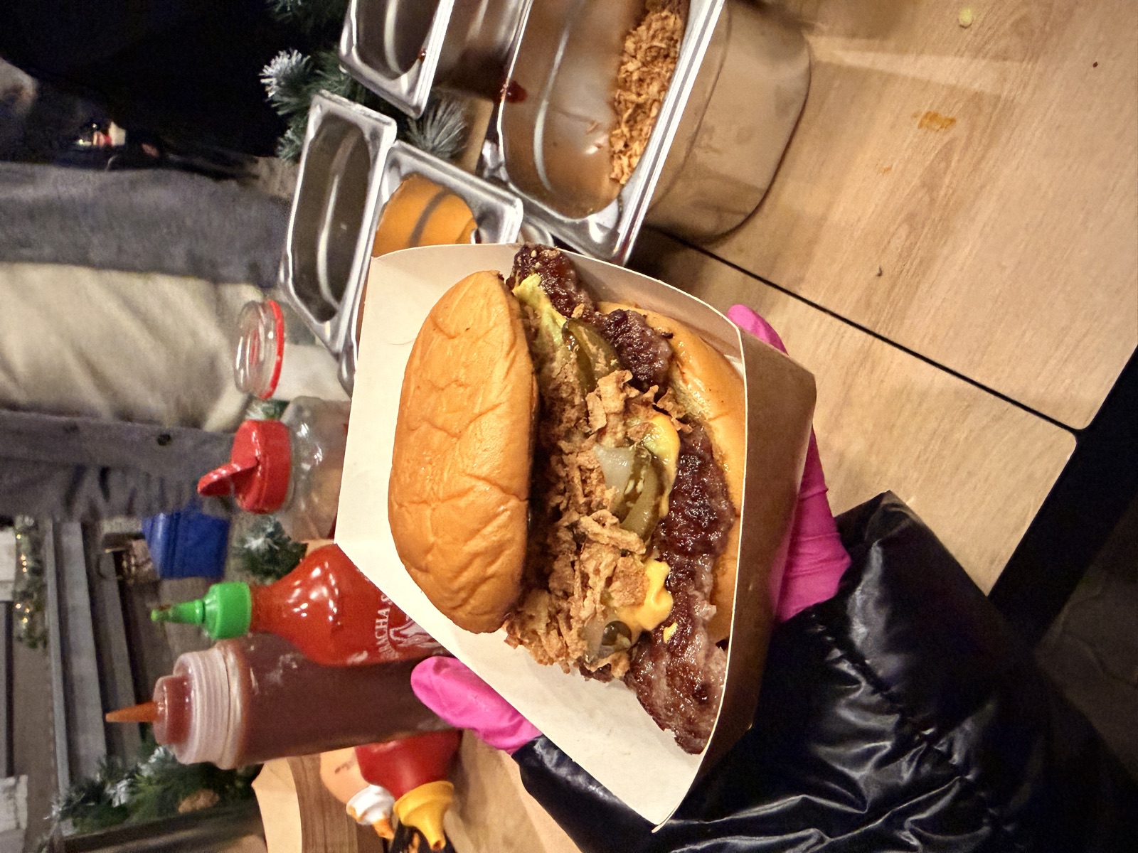 Fertiger Burger im Servierkarton, im Hintergrund die Saucen-Station