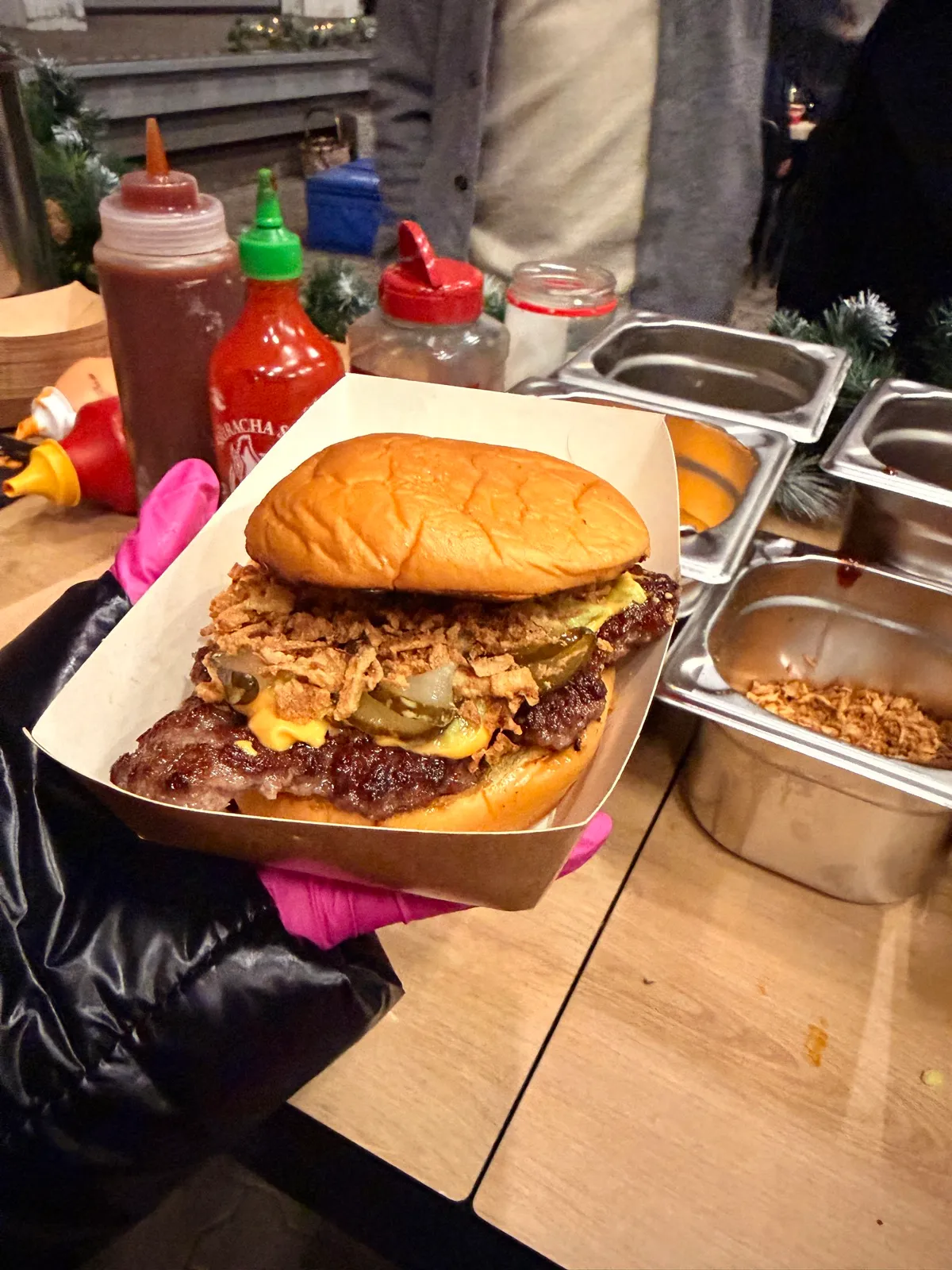 Fertiger Burger im Servierkarton, im Hintergrund die Saucen-Station