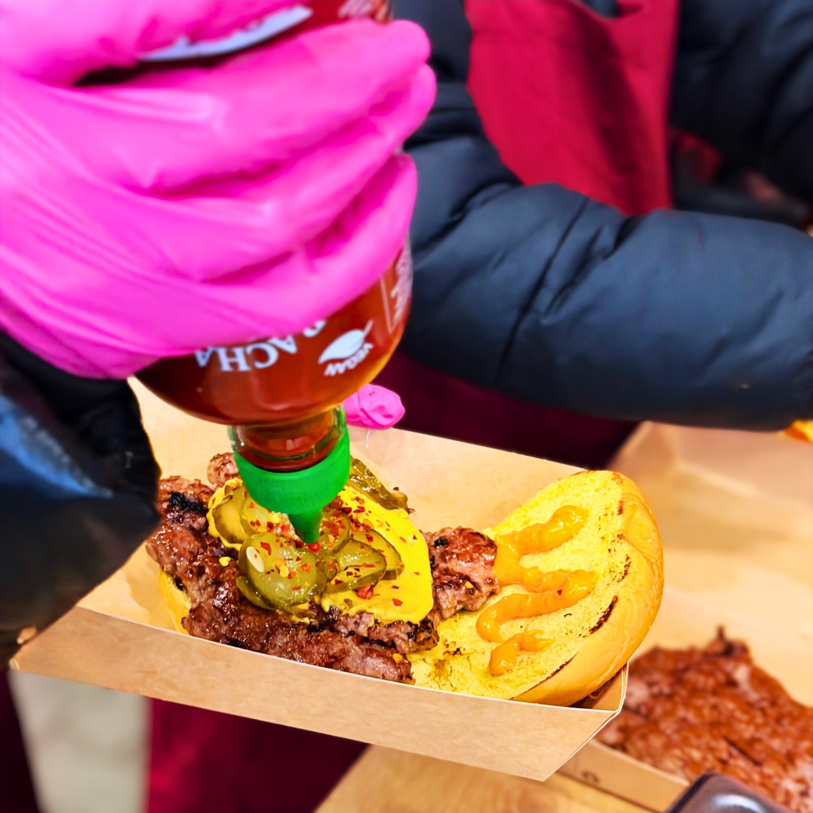 Chili-Cheese-Soße wird über einen frisch gesmashten Patty gegossen