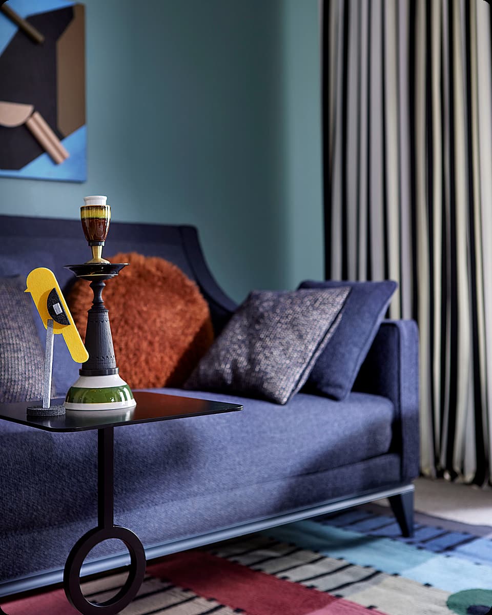 Blue sofa with textured pillows and a black side table holding decorative objects in a colorful living room.