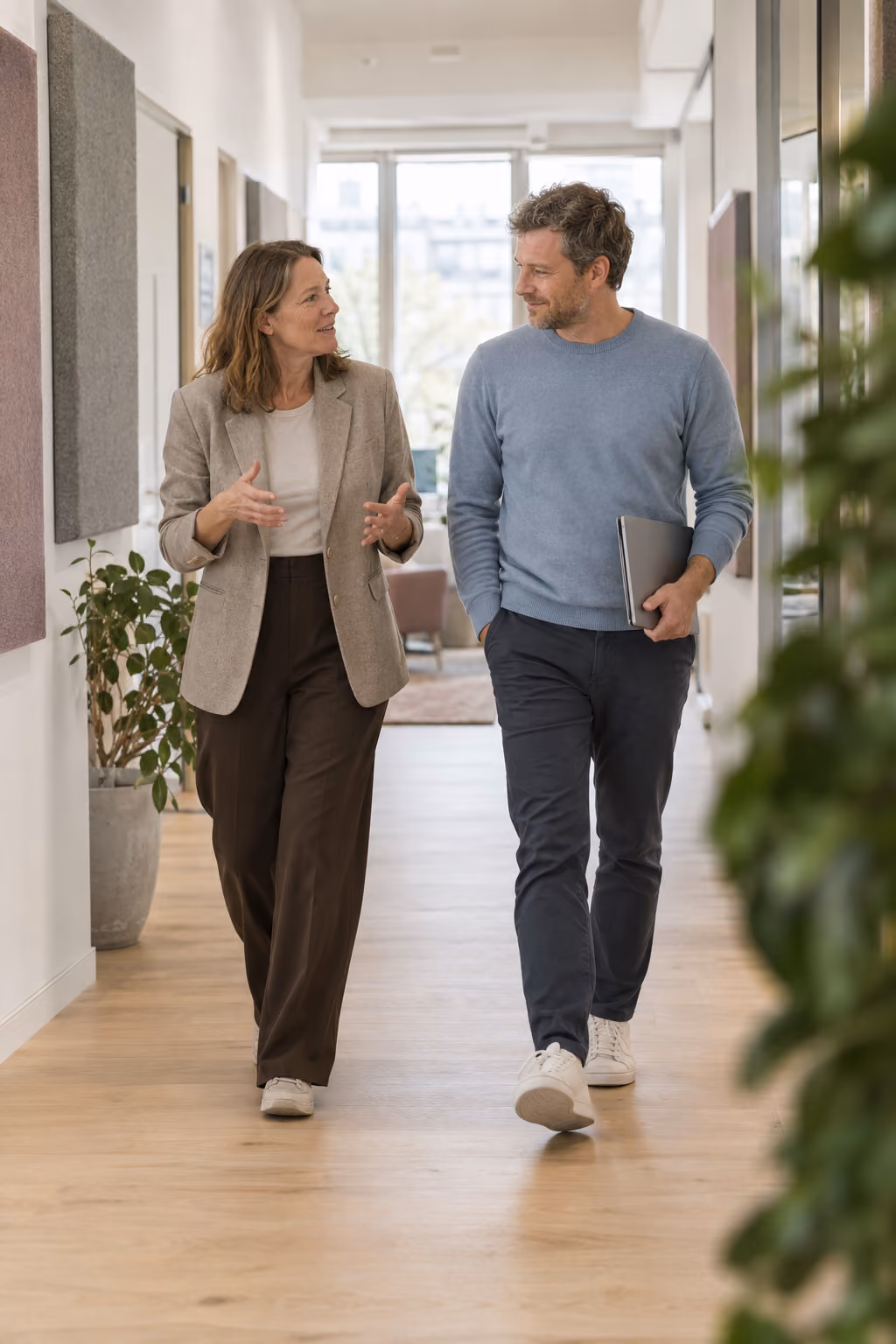 Eine Frau unterhält sich mit einem Mann beim Gang durch einen Büroflur